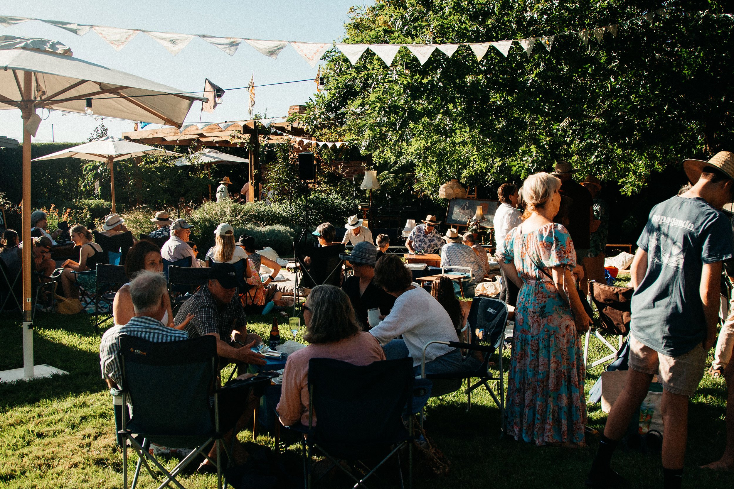 A diverse group of individuals sitting on chairs and tables in a serene grassy area.