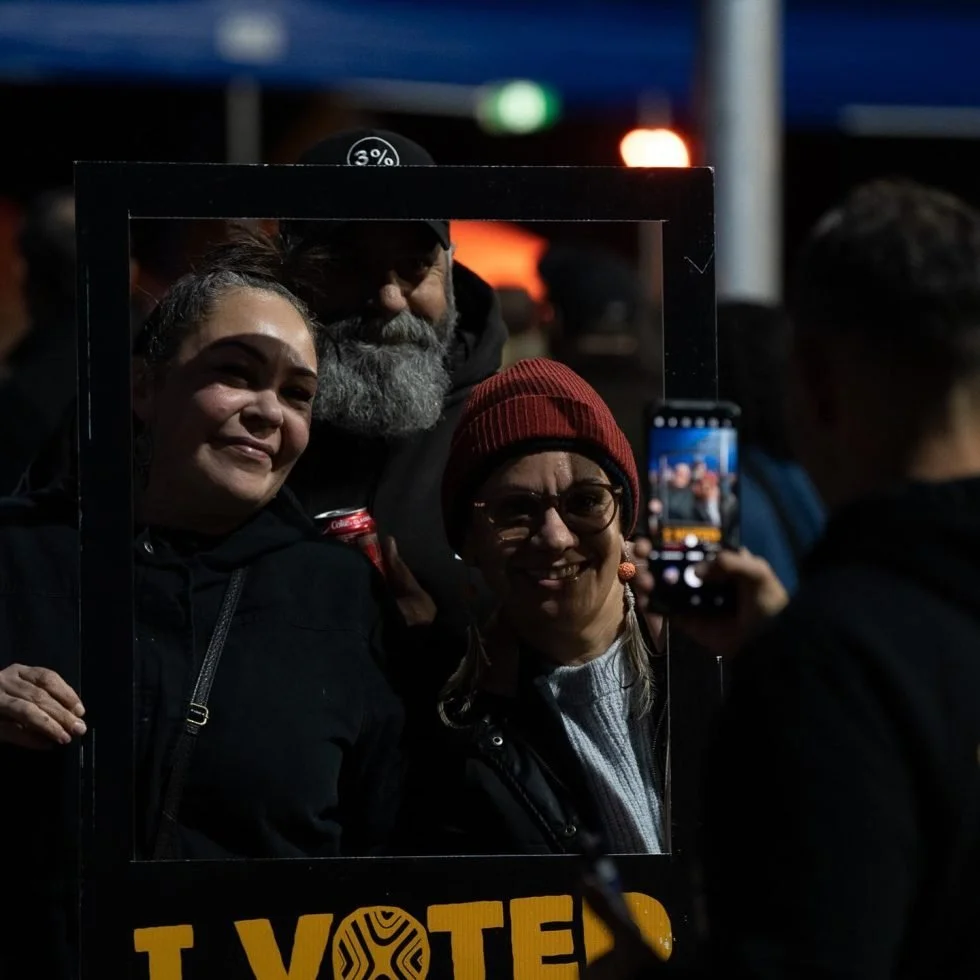 Selfie moment captured as woman poses with two others by "I Voted" sign on Treaty Day Out.