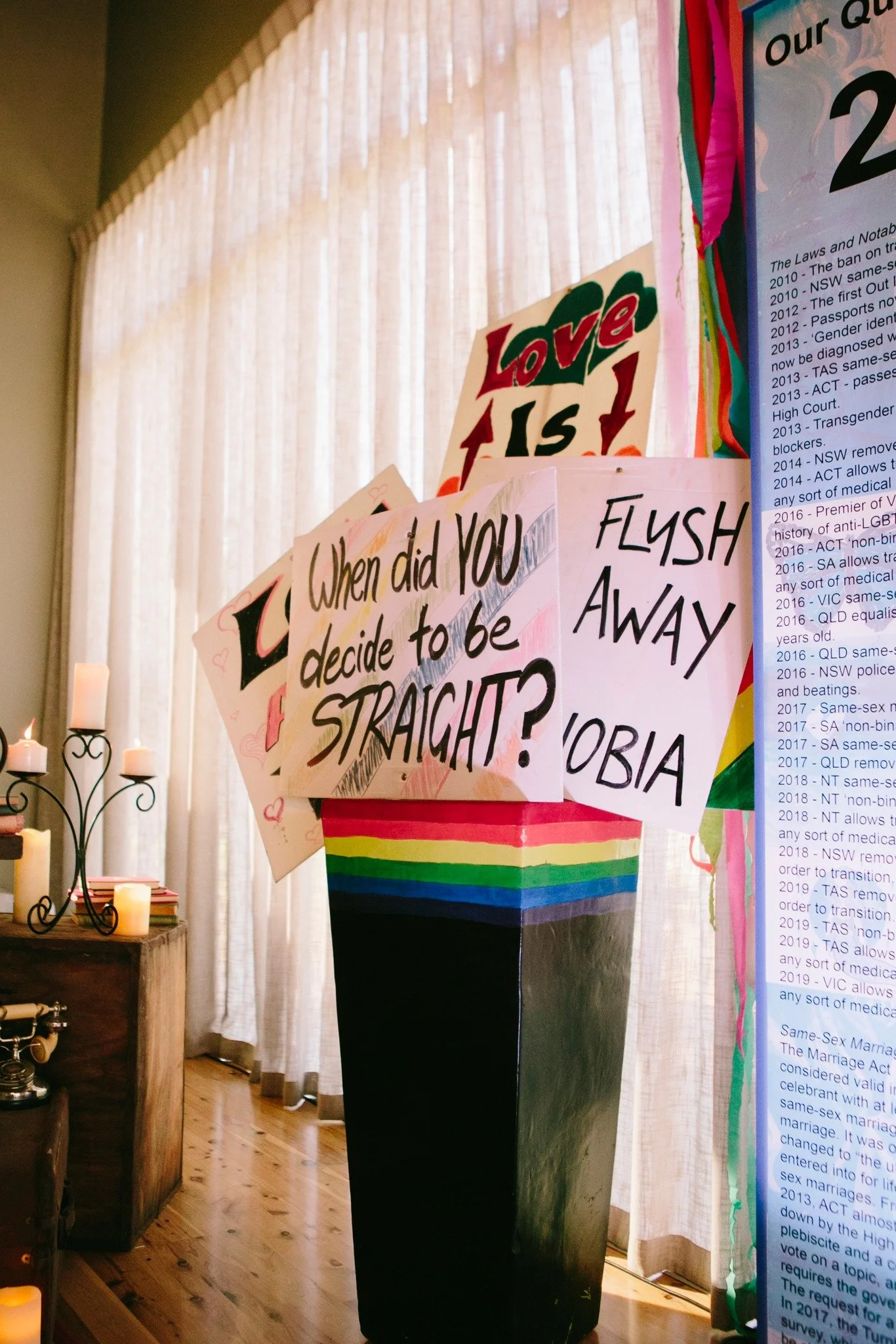 A vase with signs and a rainbow flag, perfect for Pride Ball decor.