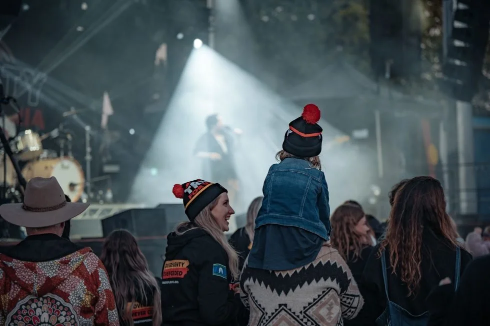Concert attendees gather around as a man lovingly holds his child at Treaty Day Out.