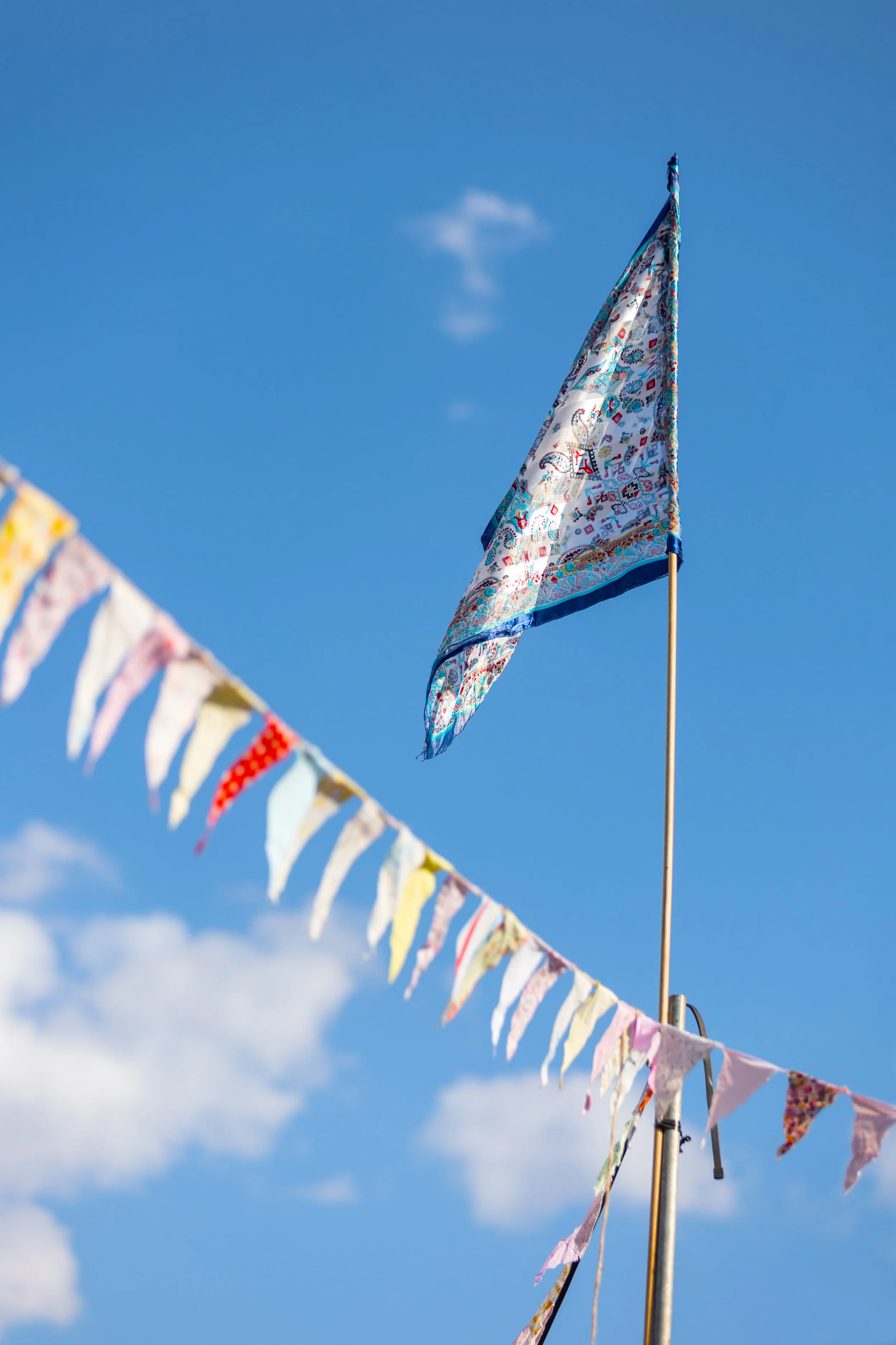 A decorative flag with bunting flying against a bright blue sky.