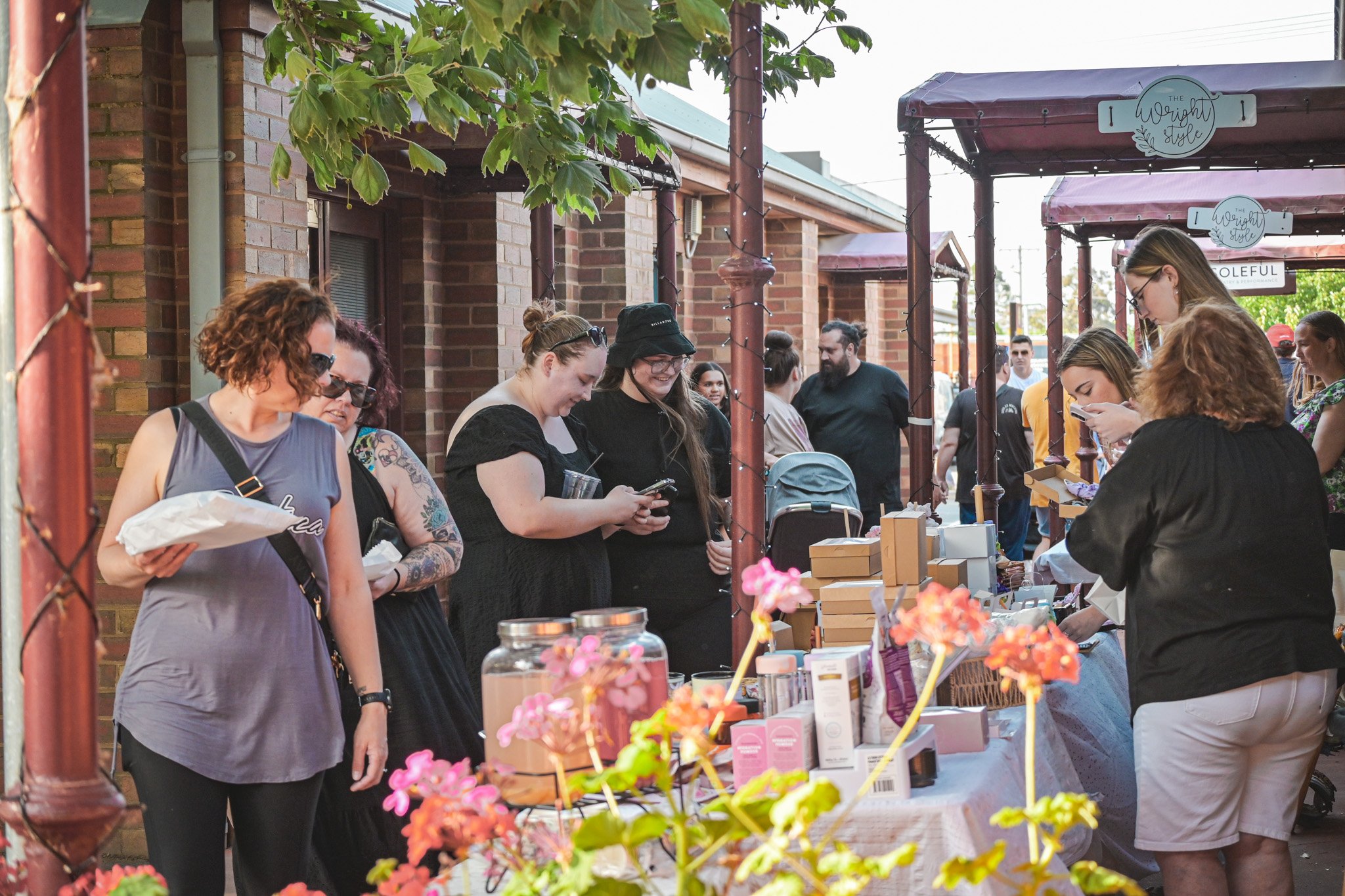 A group of people standing around a table with flowers and food.