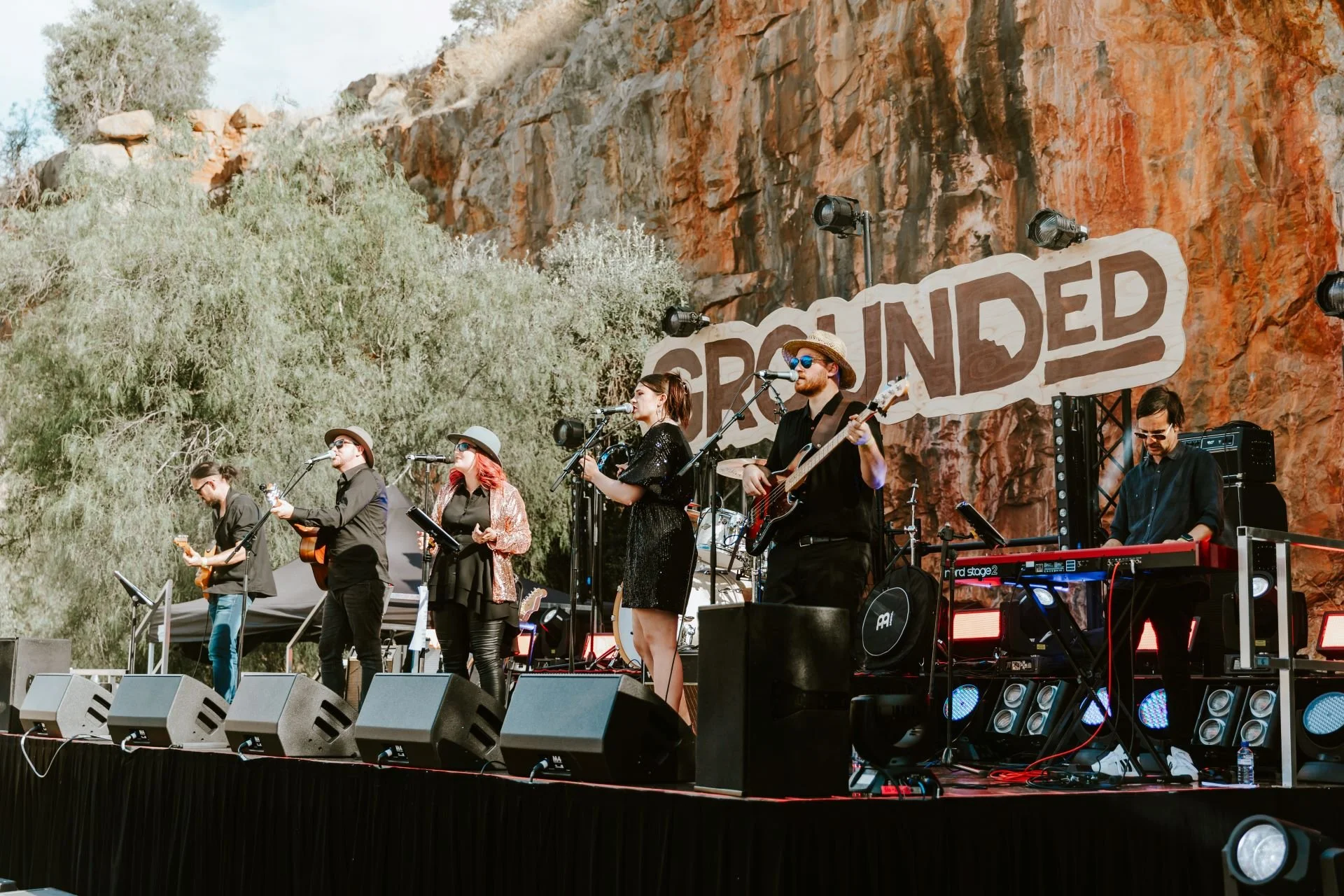 Silhouettes of people enjoying live music at a festival with bright stage lights.