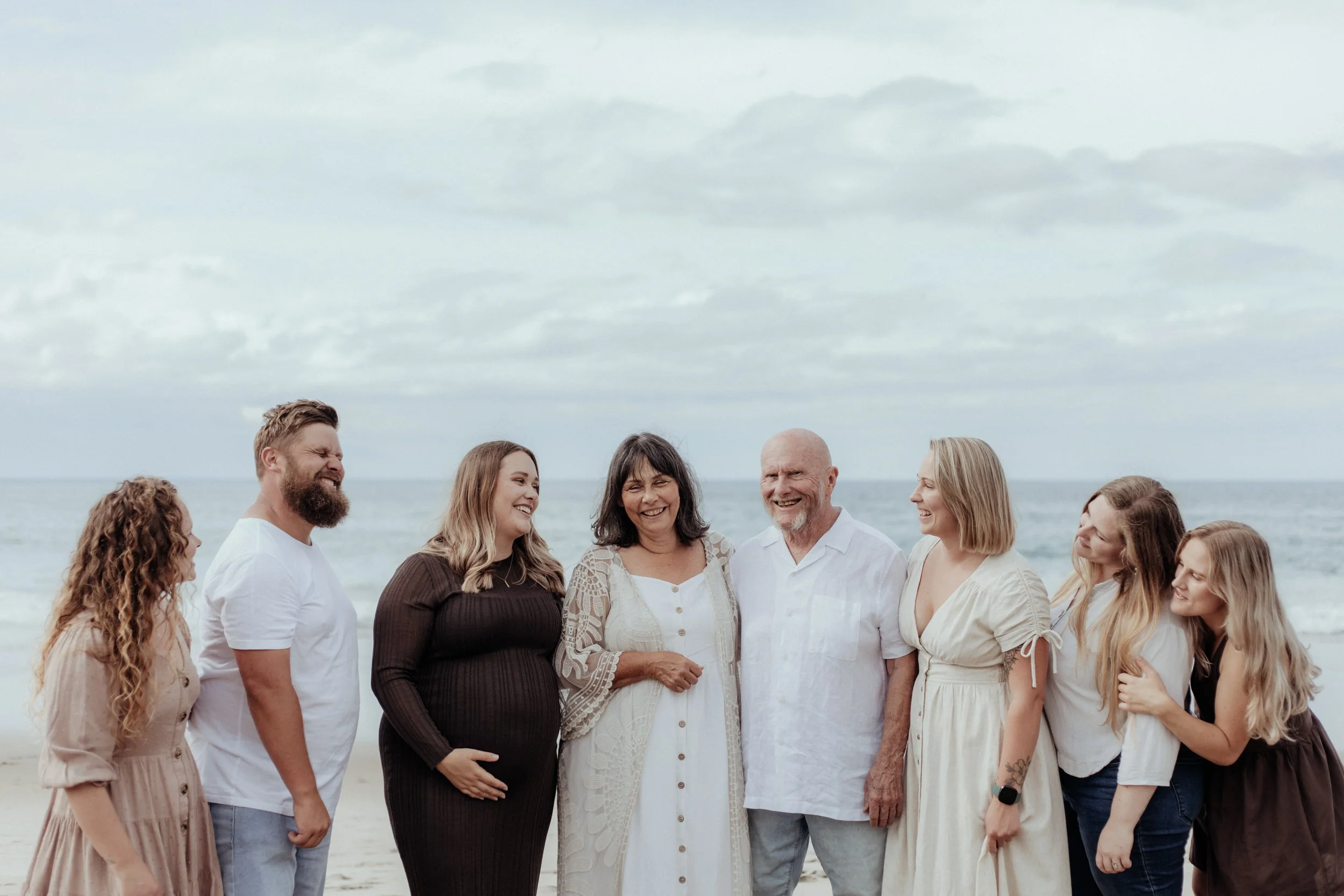 Parents and children laughing during family session at Ocean's Beach, Whangarei.