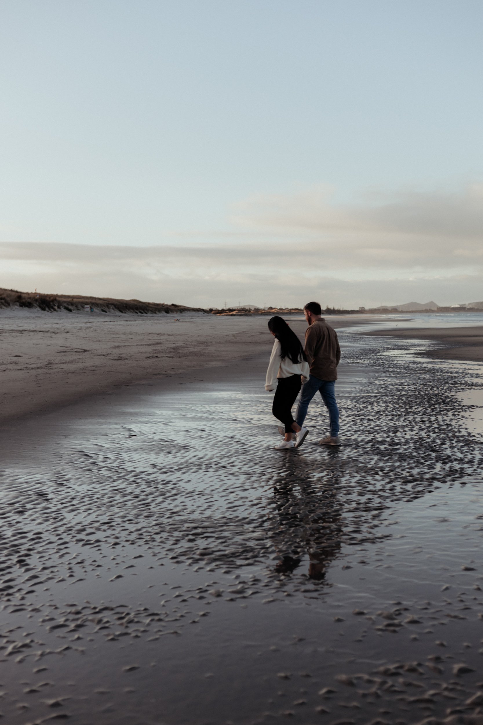 Newly engaged couple on a Whangarei beach at dusk.