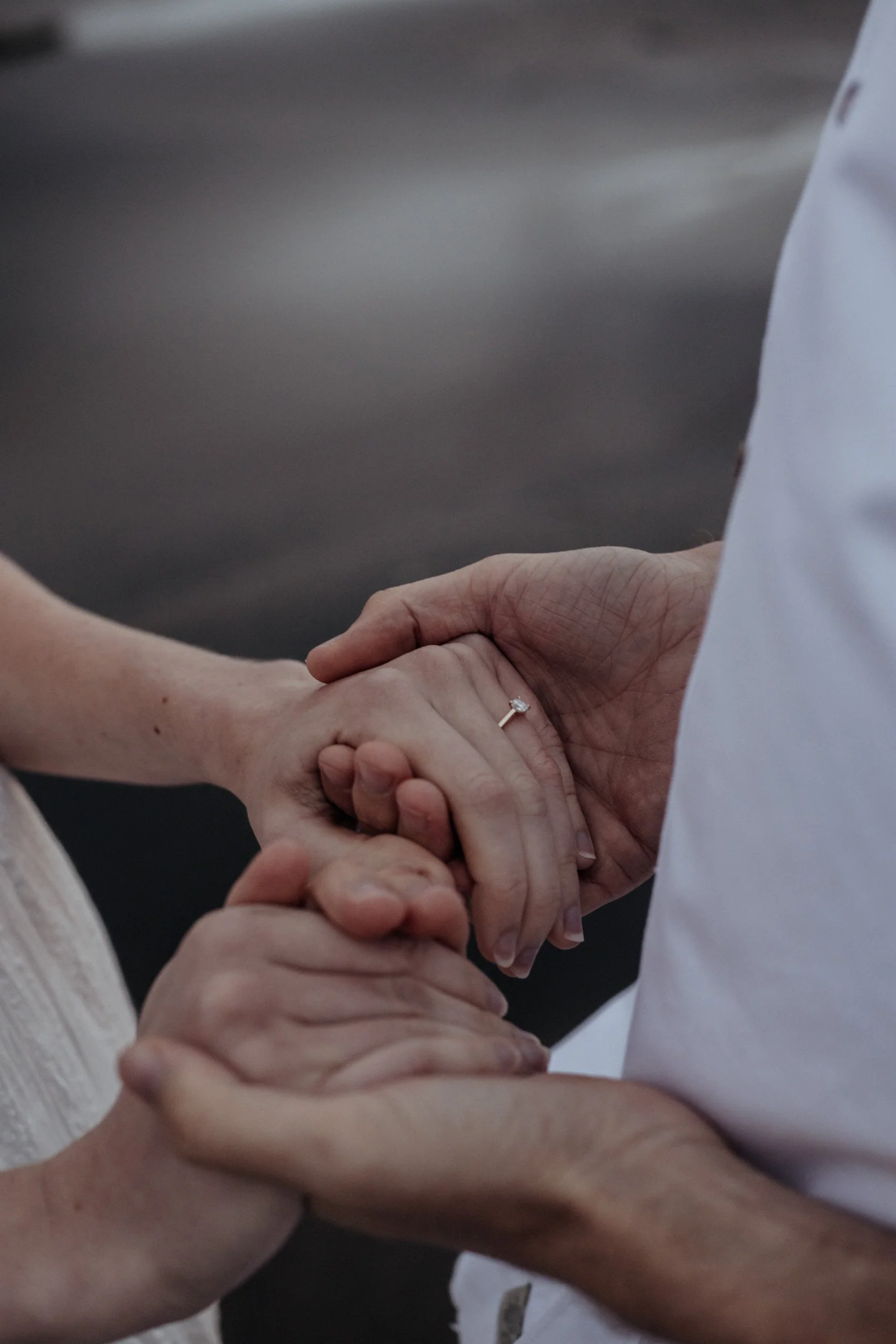 Newly engaged couple hold hands while at Piha Beach during couple photoshoot.
