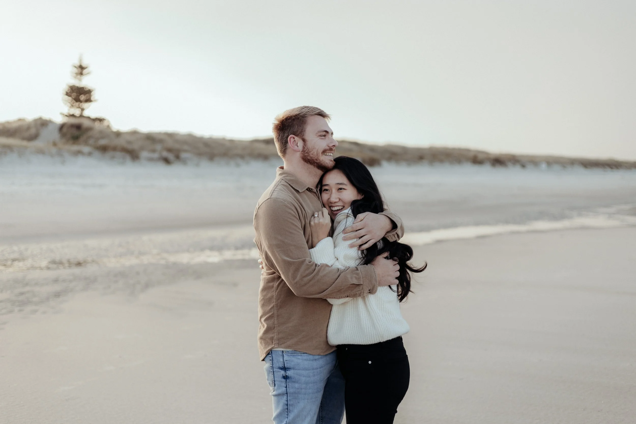Newly engaged couple embracing at Northland beach photoshoot.