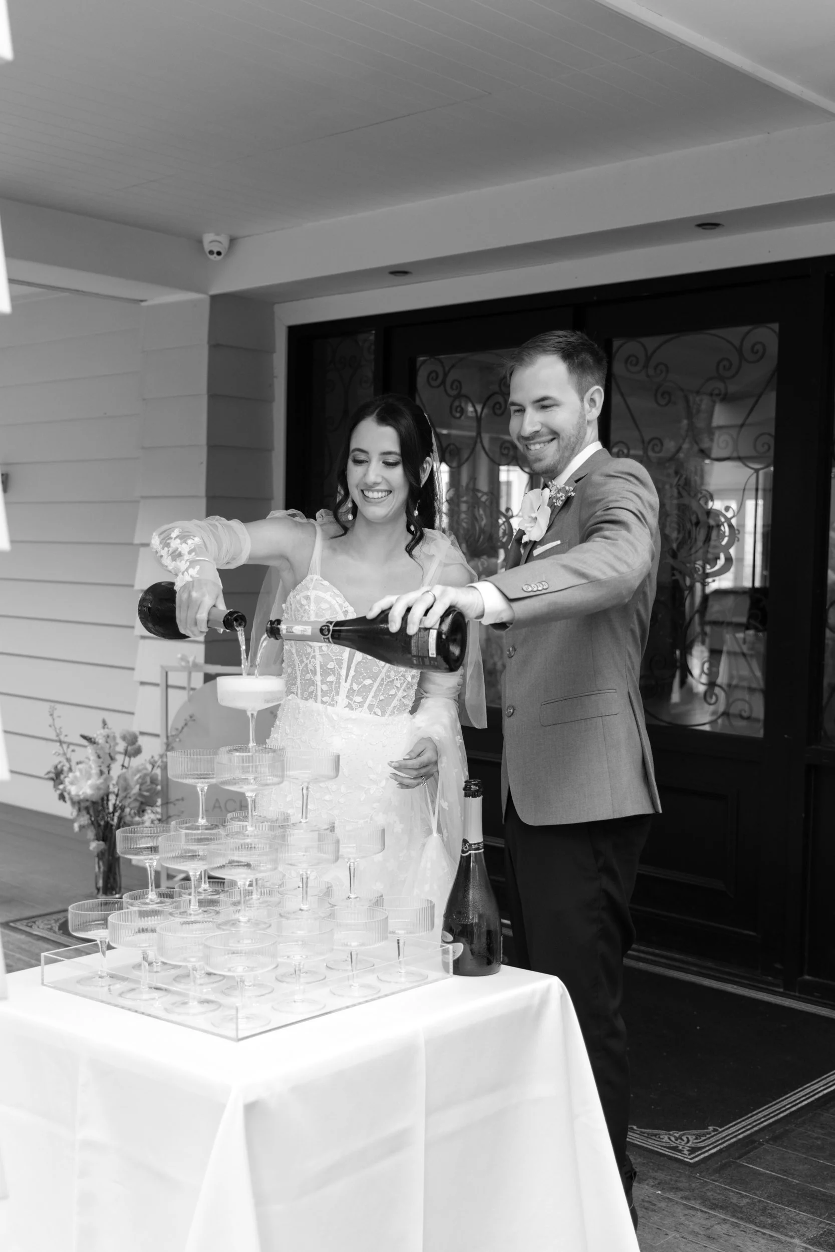 Bride and groom filling champagne tower at Bracu Estate wedding in Auckland.