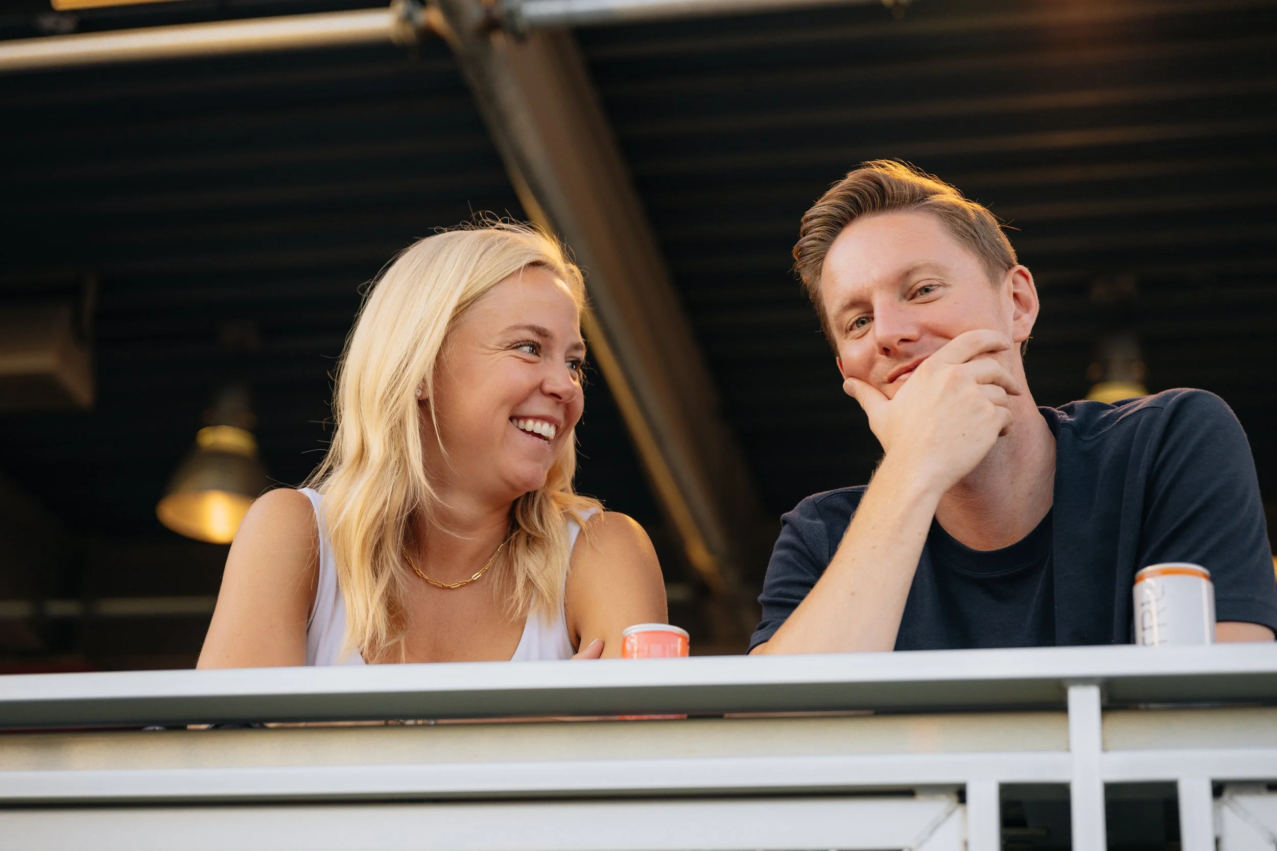 A woman and a man sitting at a table, smiling and laughing together.