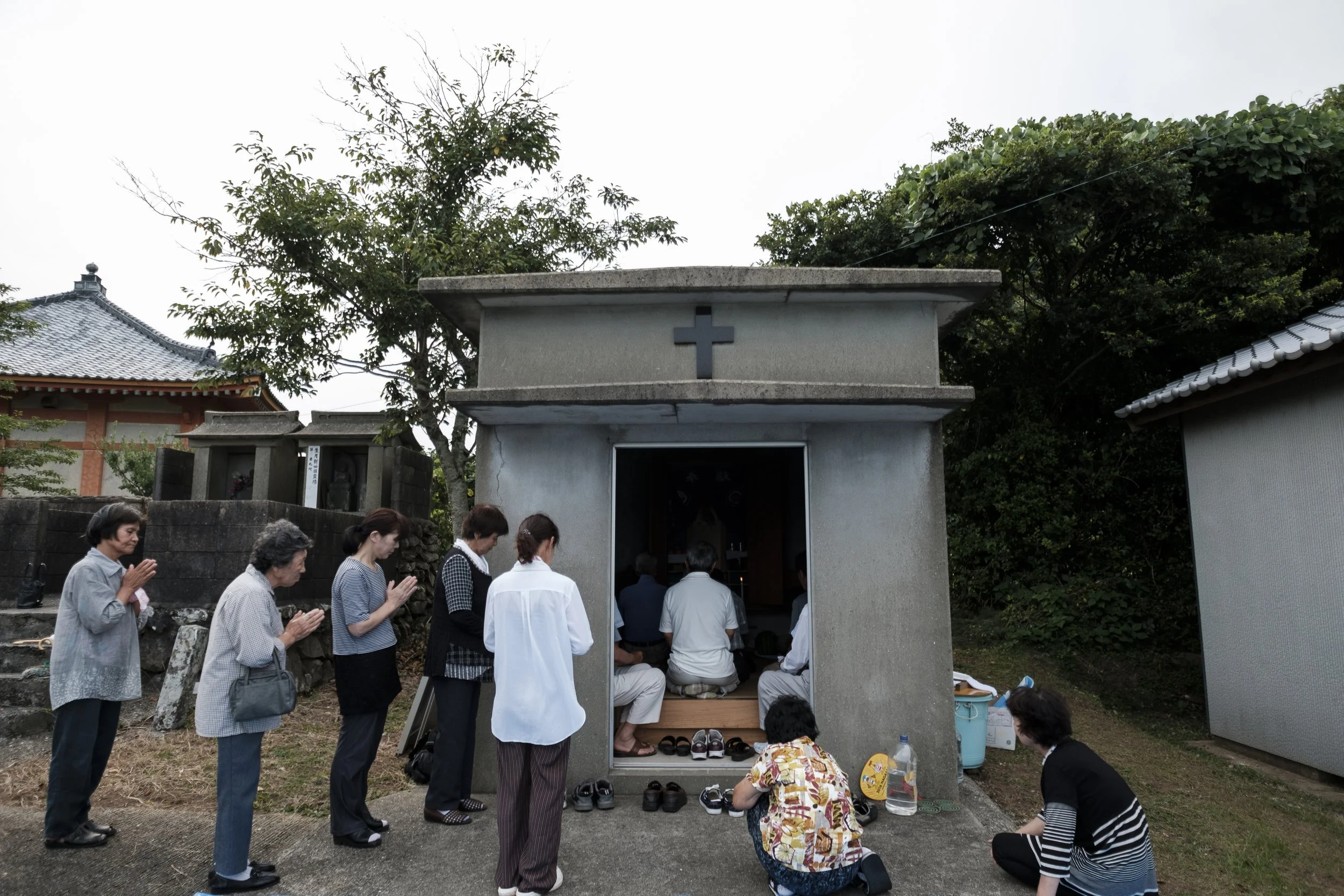 Women for hidden christian community members prays outside the small house, separately for men during a ceremony for summer (and middle of the year).