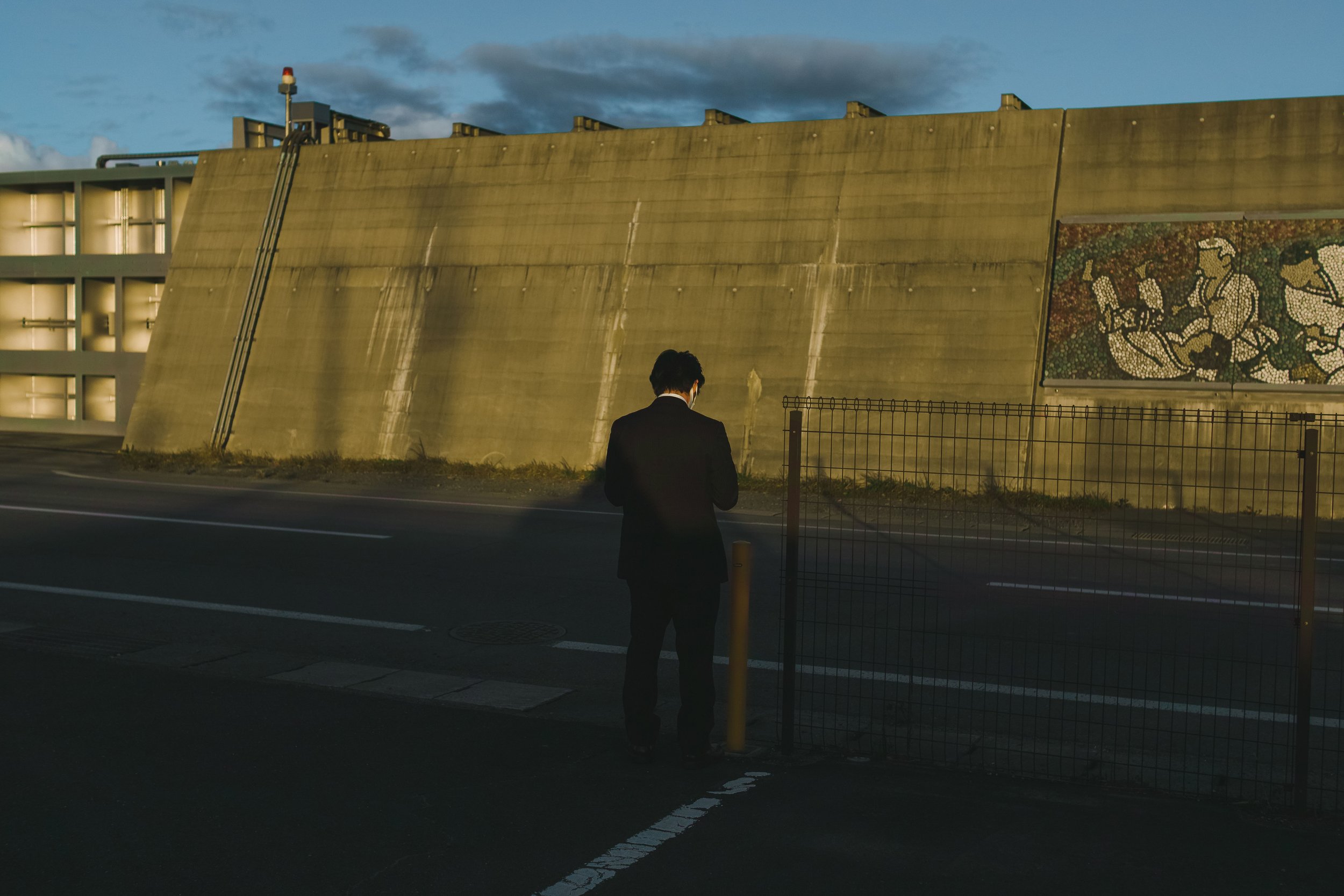 A man wearing a suit waits in front of a sea wall in Kuji city, Iwate, Japan.
