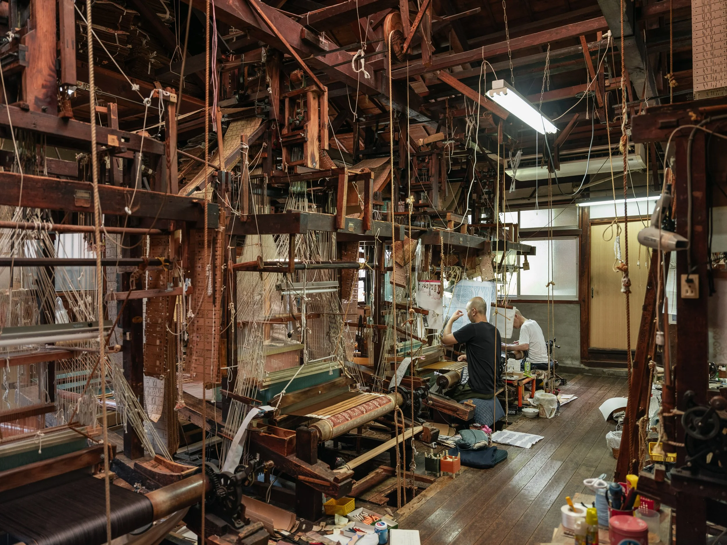 An employee works at a loom in a workshop producing costumes for Noh theatre.