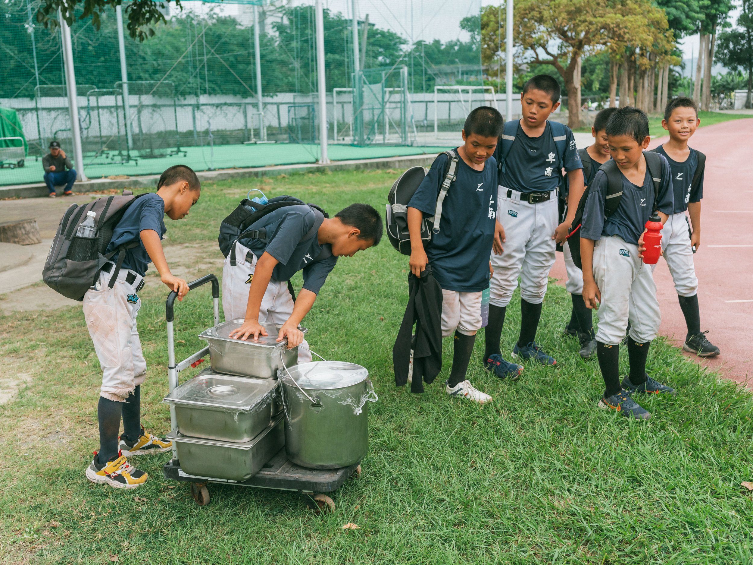 The children from the baseball team who stay at the boarding school are moving the evening meal.