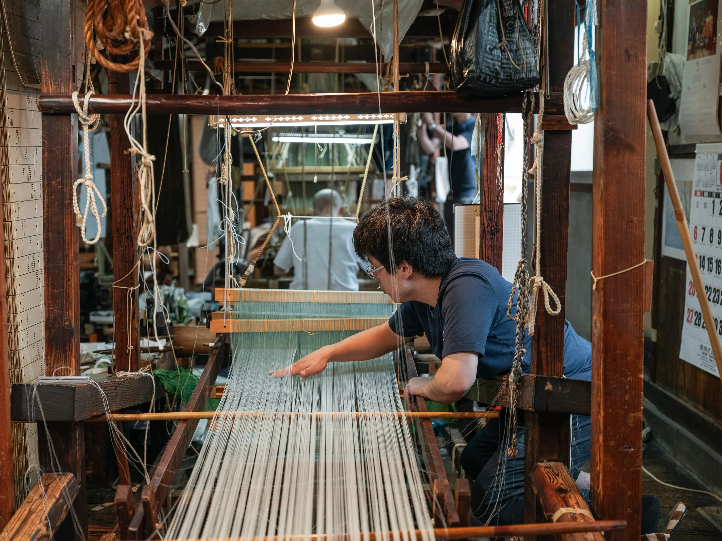 An employee works at a loom in a workshop producing costumes for Noh theatre.