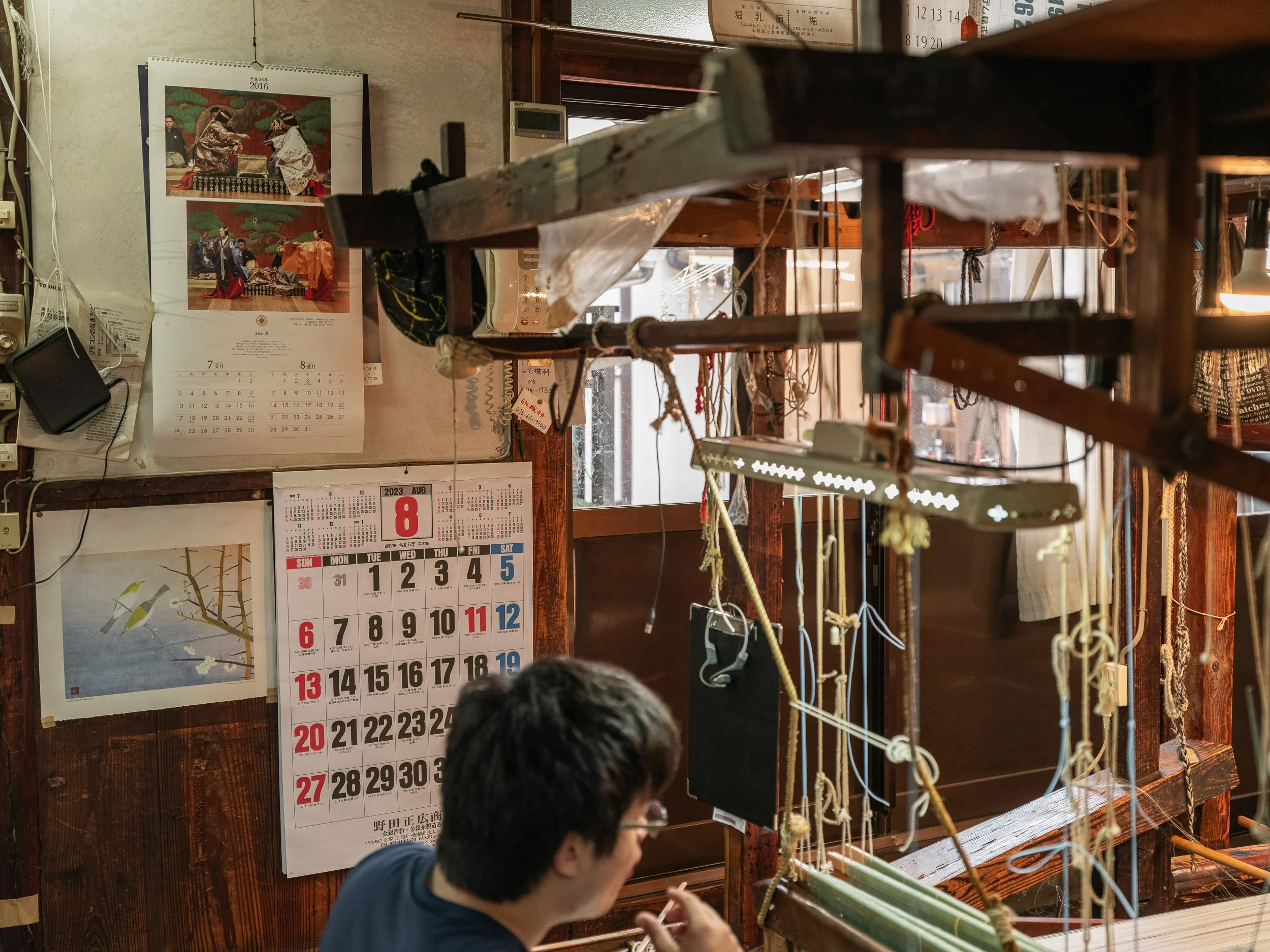 An employee works at a loom in a workshop producing costumes for Noh theatre.
