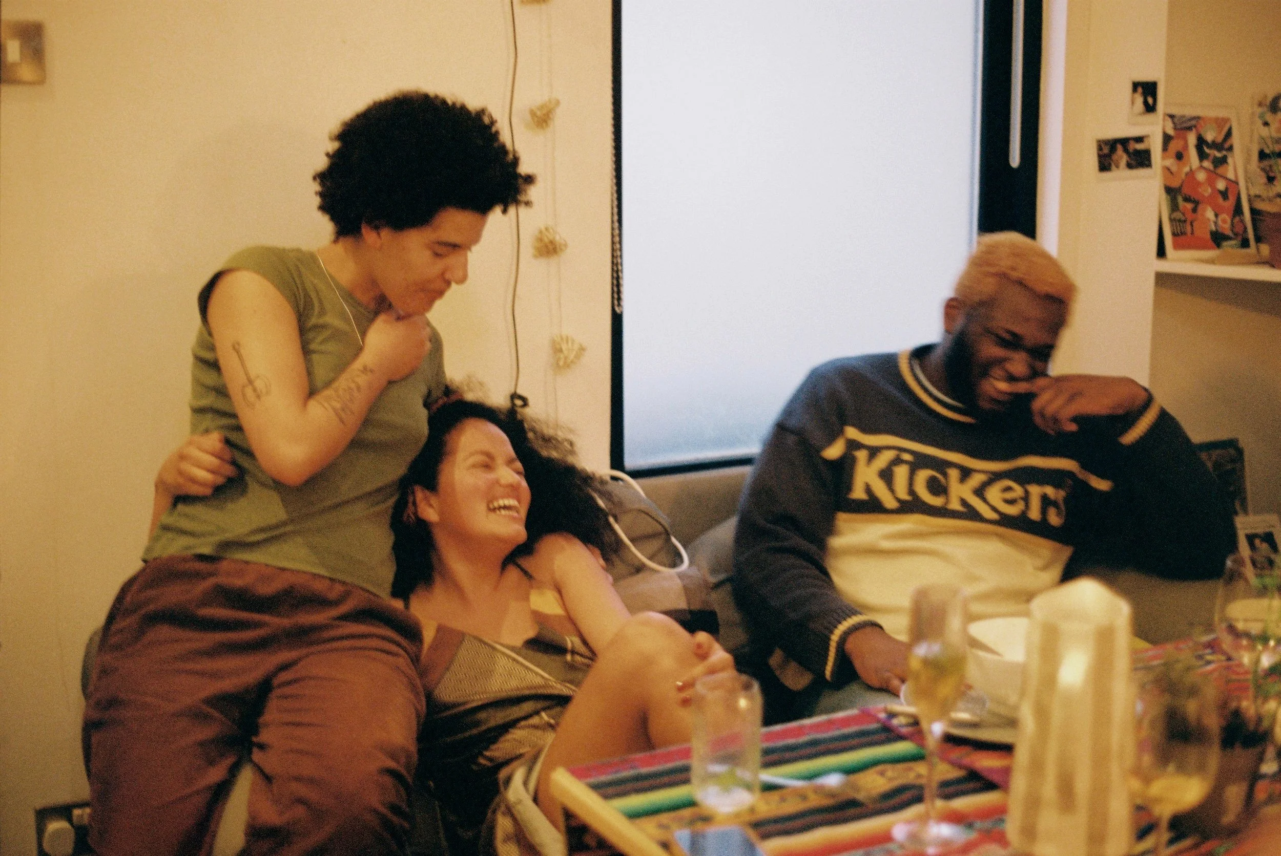 3 friends sitting on a couch laughing.