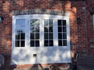 A large white window with multiple panes set into a brick wall.