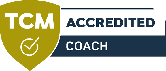 Logo with a green shield on the left with white text 'TCM', and text 'ACCREDITED COACH' on a horizontal dark background.
