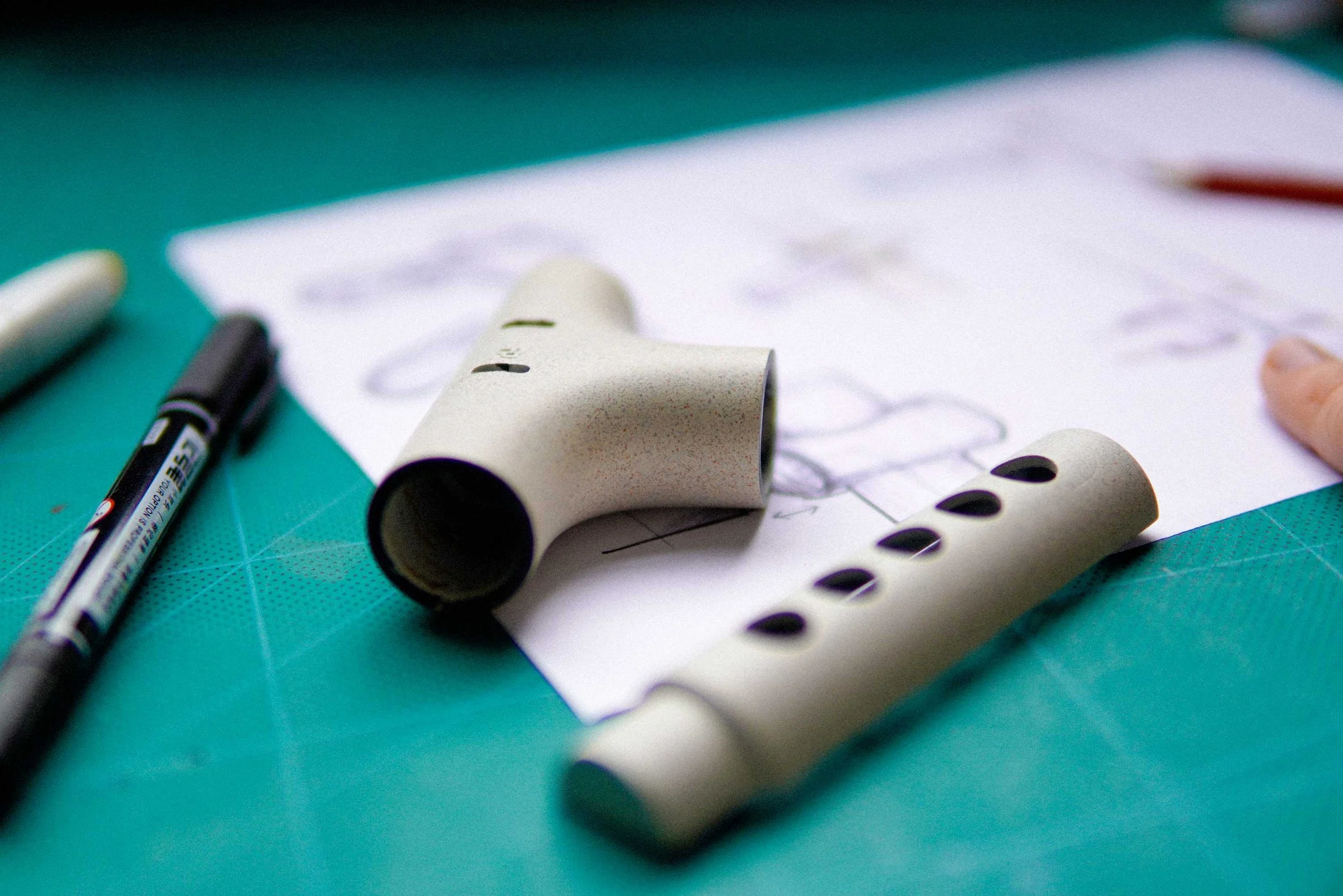 Close-up of a sheet of paper with handwritten notes, a black marker, and multiple bubble tea straw wrappers on a green cutting mat.