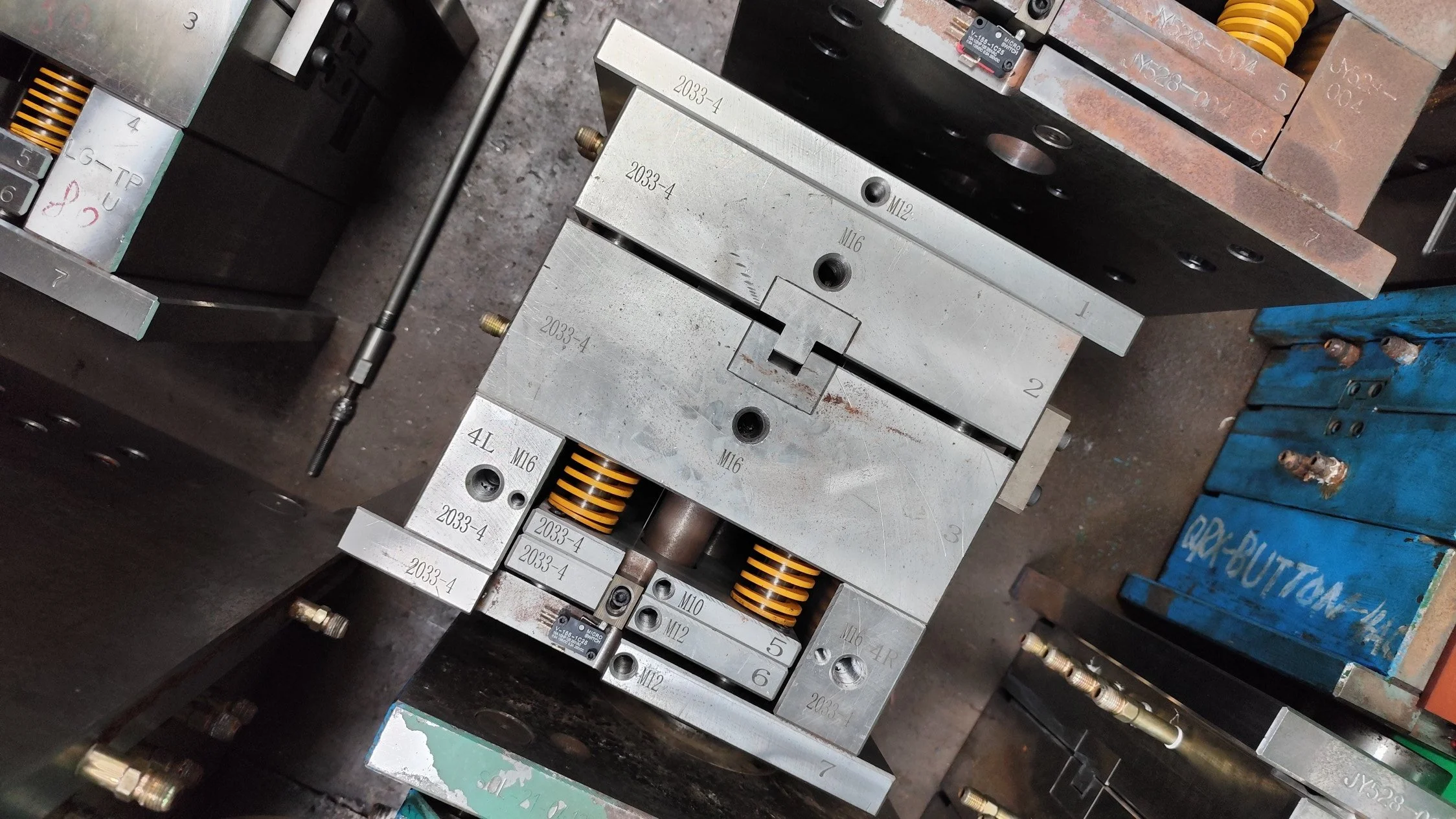 Close-up of industrial machine parts including metal blocks, springs, screws, and electronic components.