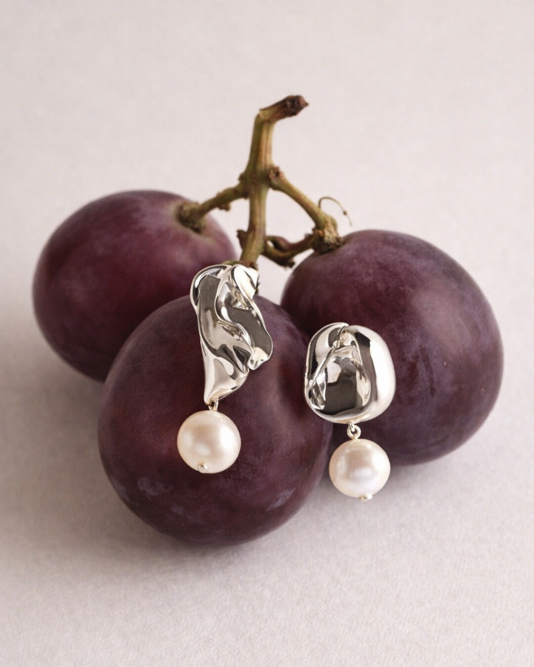 Still life photography of silver jewelry on grapes.