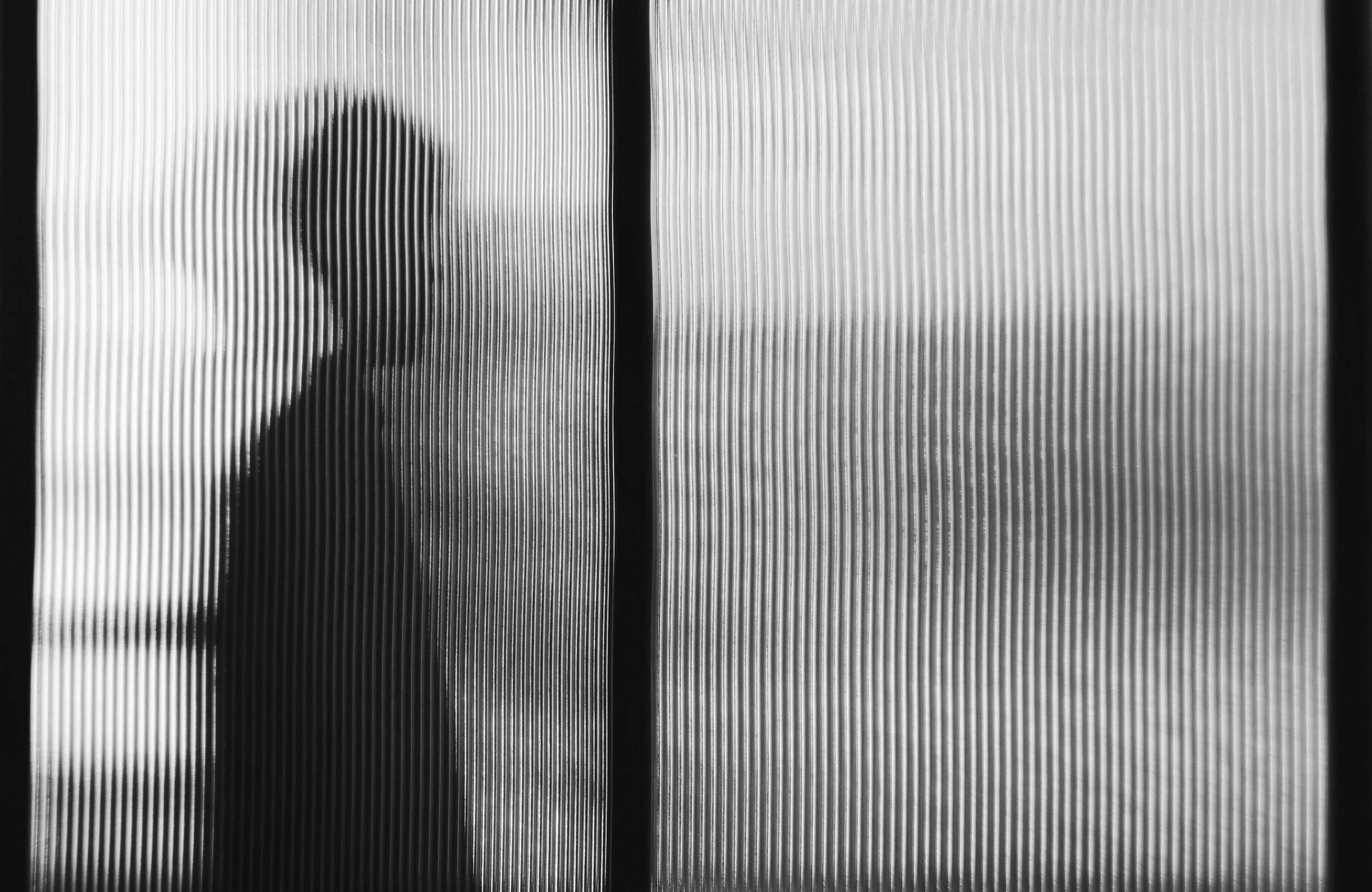 Silhouette of a person behind a textured glass door or window.