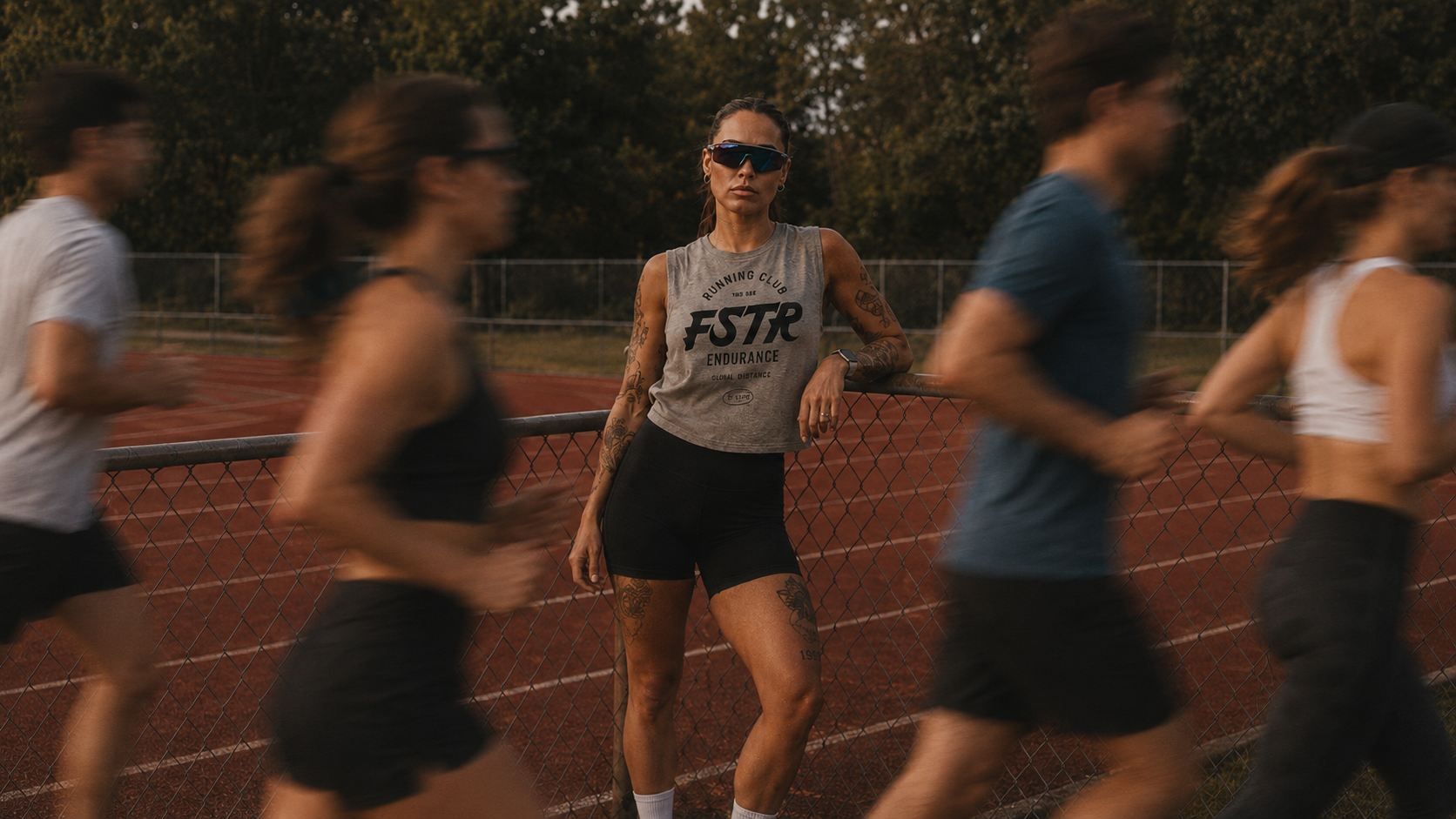 FSTR Endurance Running Club brand identity — a runner wearing the FSTR Endurance sleeveless shirt at a track, showcasing the Running Club wordmark in a lifestyle setting.