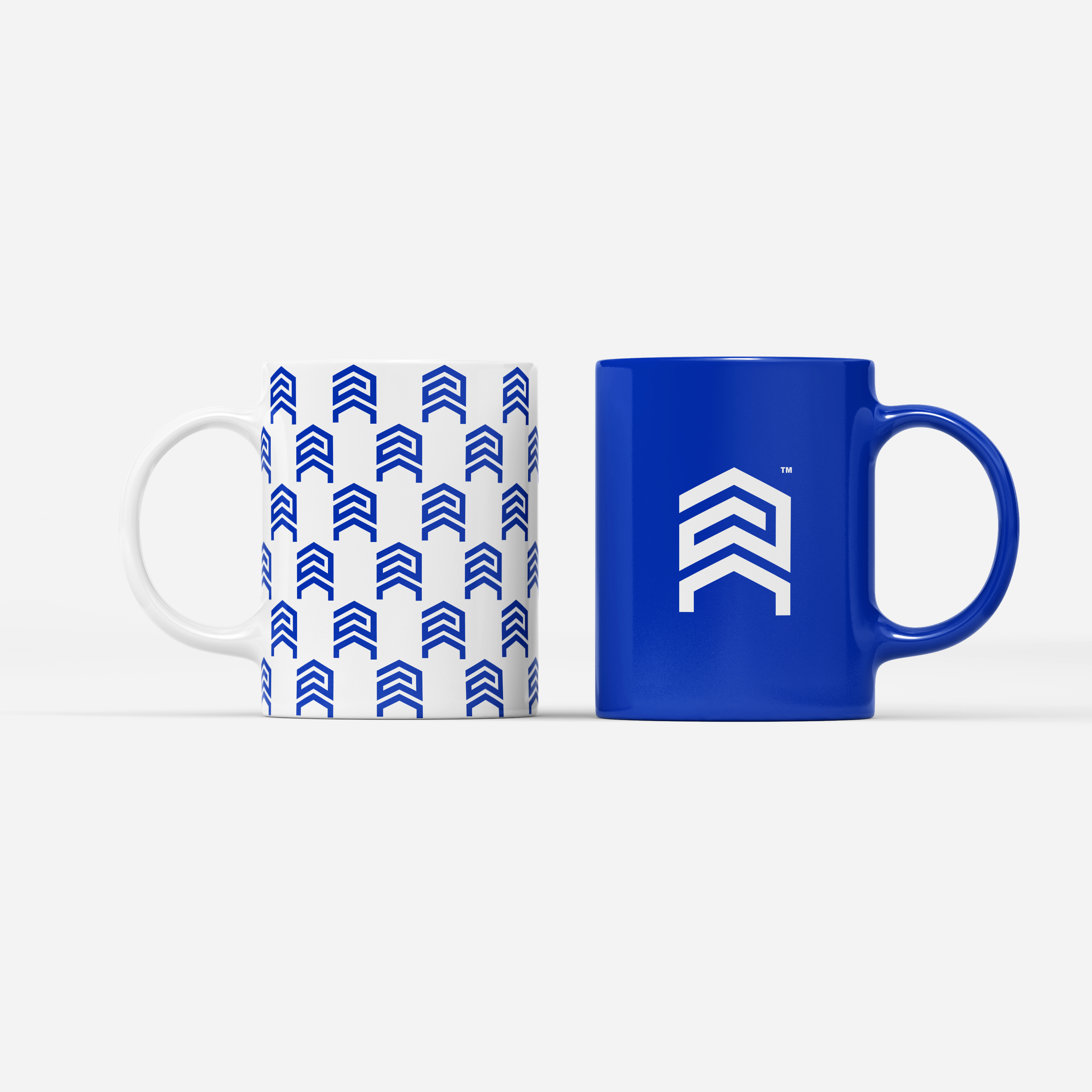 Two Apex Team branded mugs — white with blue brand pattern and electric blue with white logo — real estate promotional merchandise.