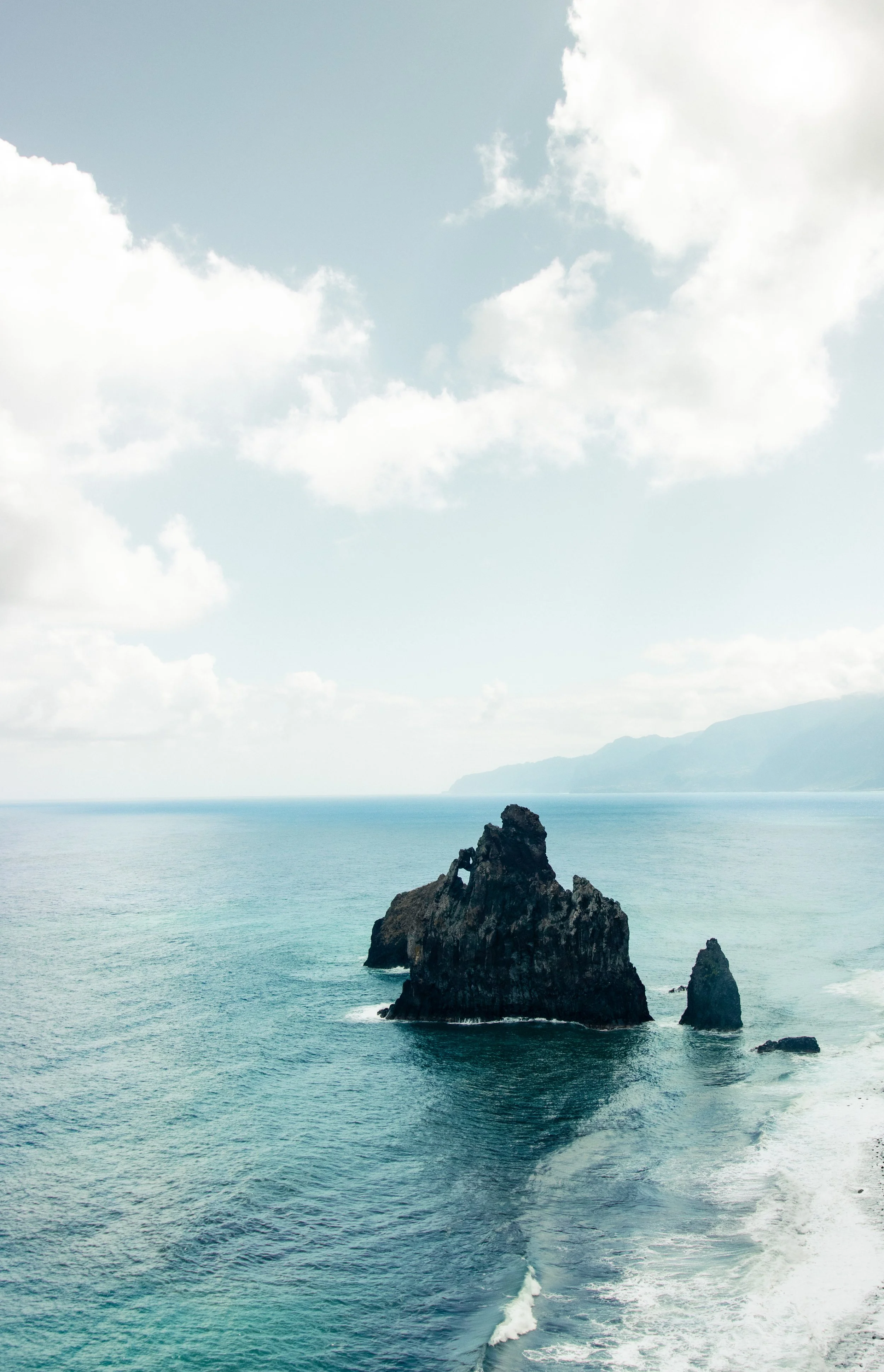 Scenic view of ocean with rock formations and a cloudy sky.