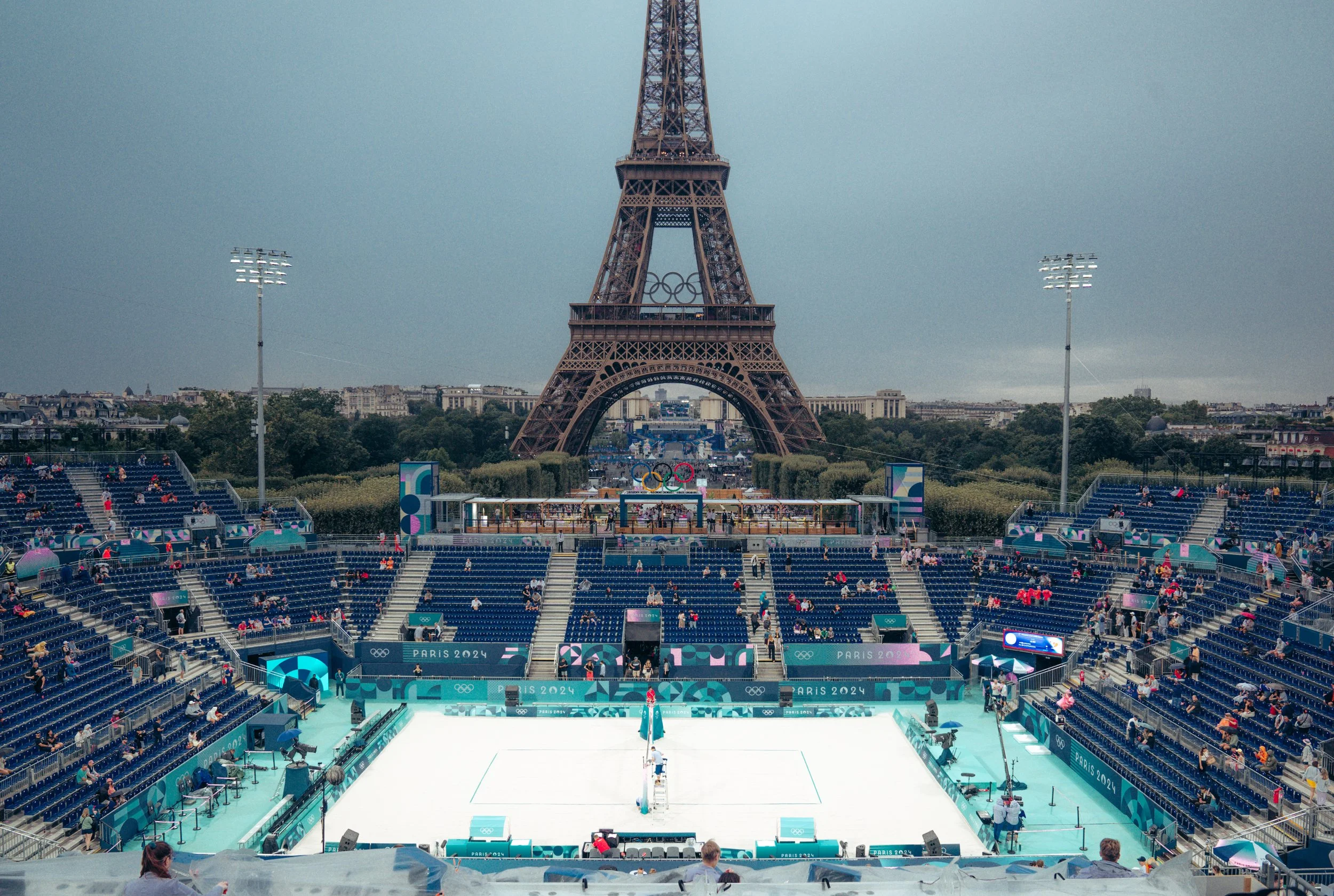 An outdoor Olympic ice skating rink with the Eiffel Tower in the background, set up for the Paris 2024 Olympics.