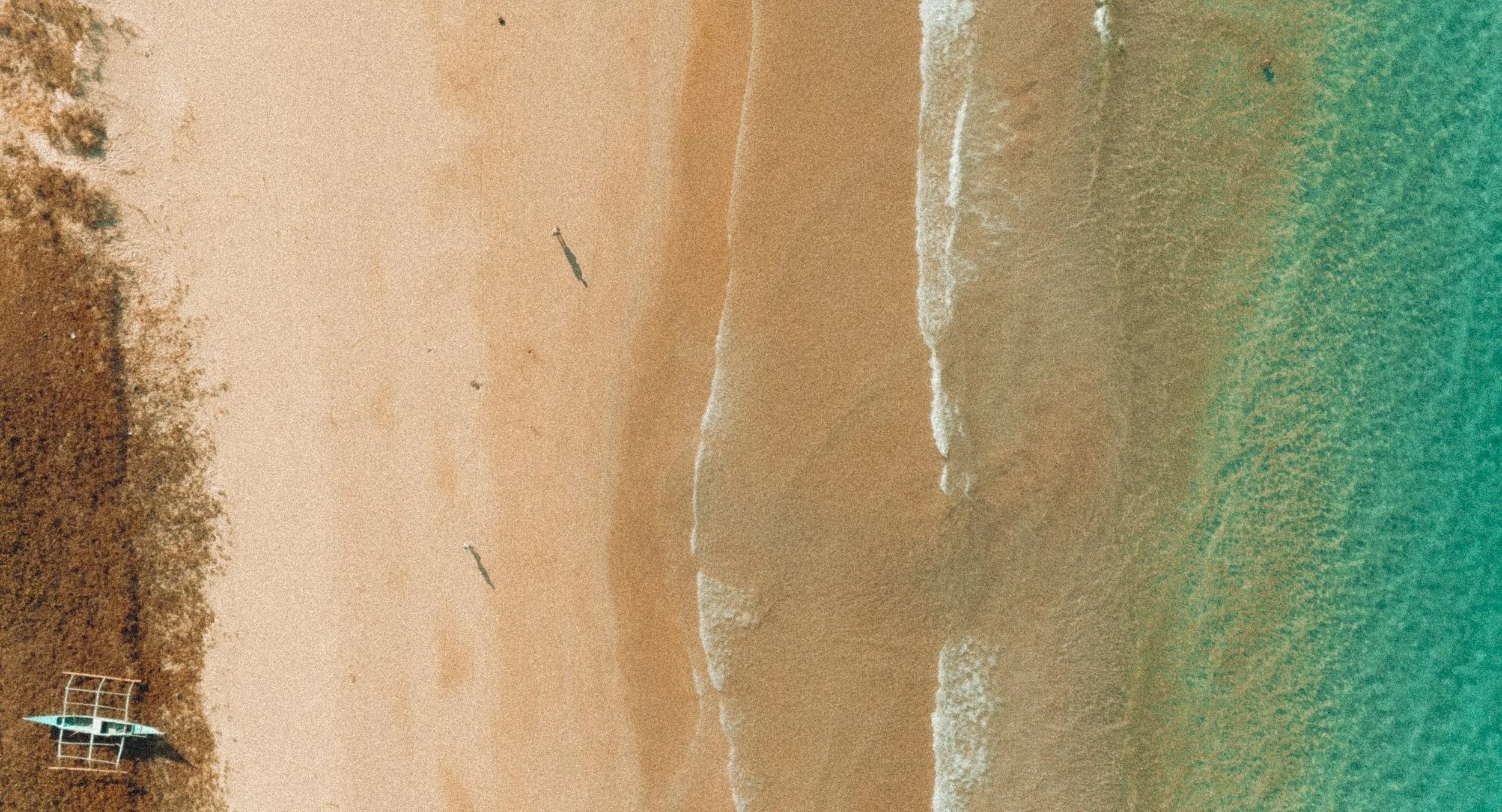 A sandy beach with a lifeguard tower on the left side, internet waves crashing near the shore, and a person parasailing in the sky.