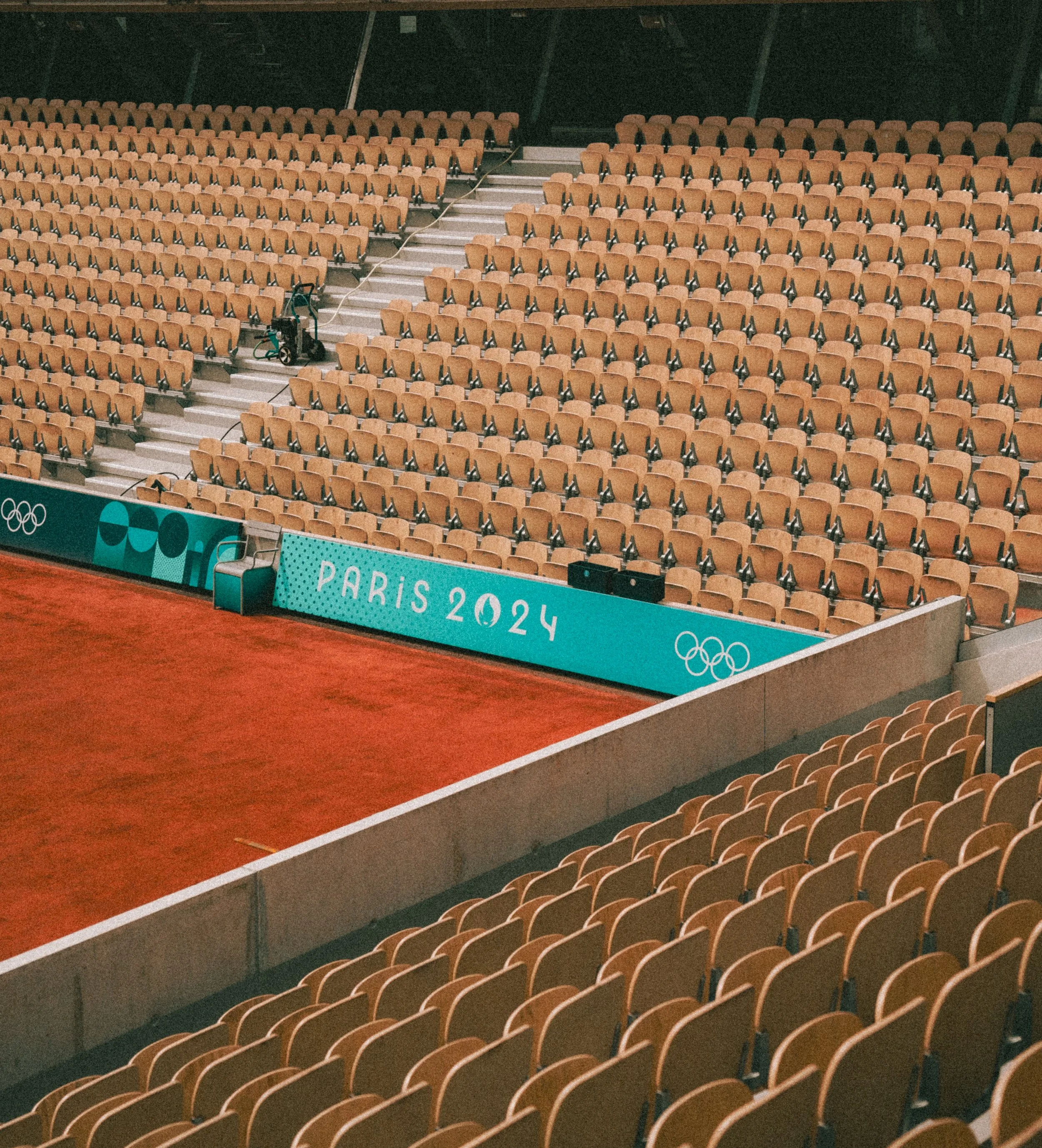 Empty seats in an Olympic venue during the Paris 2024 Olympics, with a section of the arena showing a wheelchair accessible area and Olympic branding.