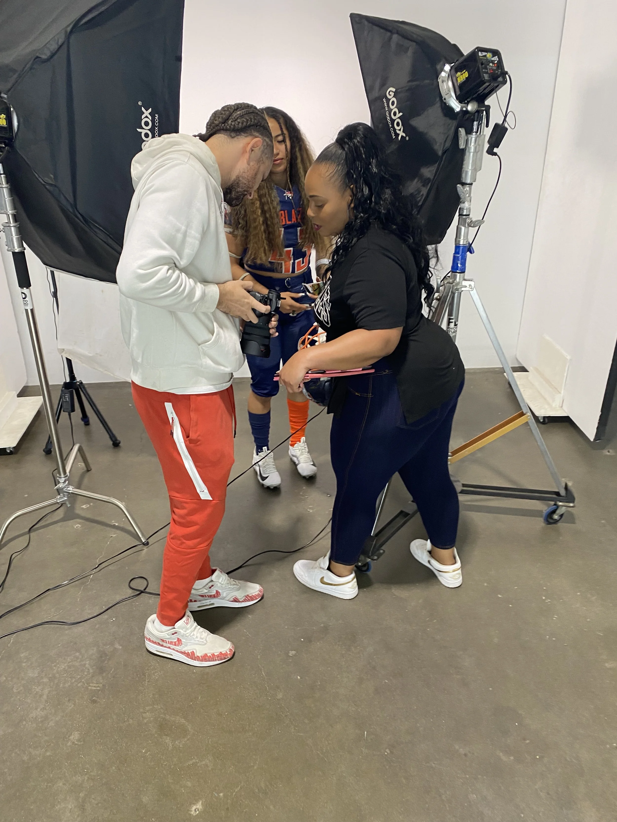 Brandee participating in a professional photoshoot behind the scenes, reviewing camera equipment and collaborating with a creative team in a studio setting for personal branding content.