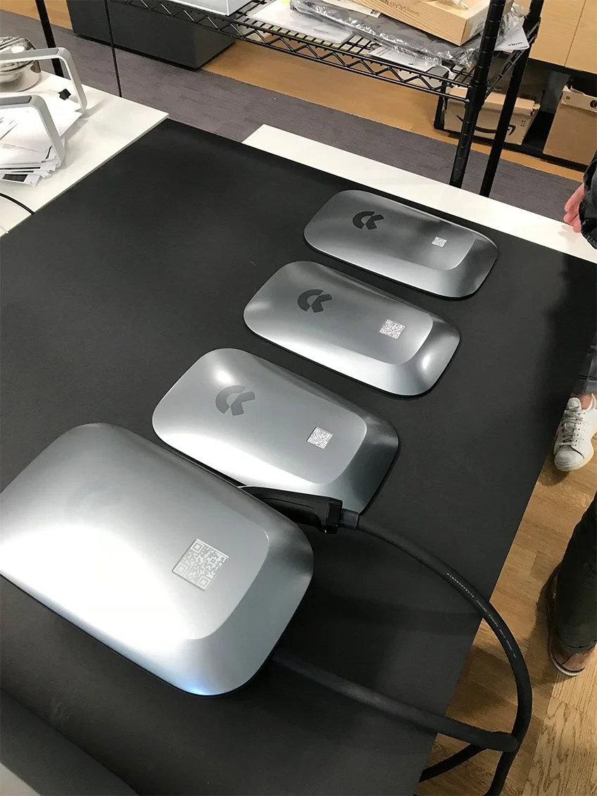 Vier kabellose Ladegeräte mit Logitech-Grafik, auf einem schwarzen Tisch, in einer Arbeitsumgebung.