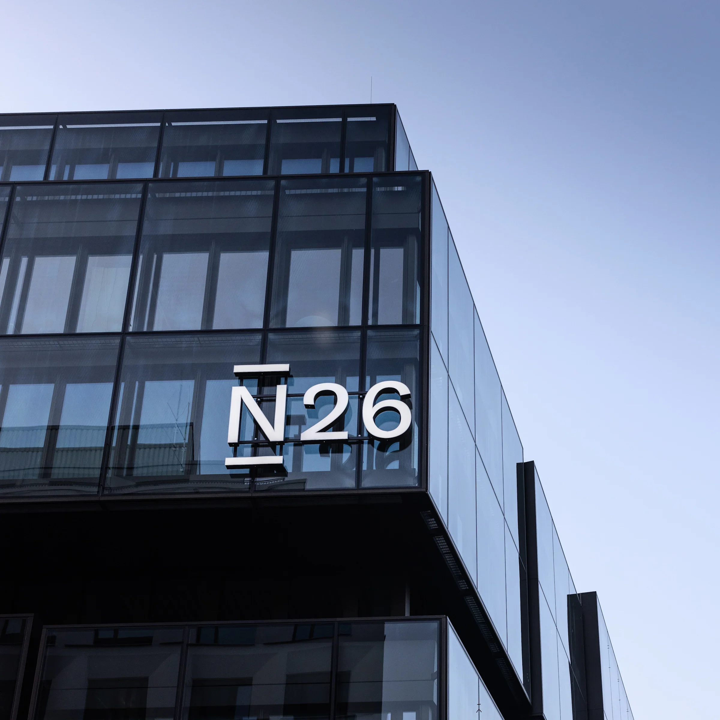 Ansicht eines modernen Gebäudes mit Glasfenstern gegen blauen Himmel, teilweise verborgen im Schatten.