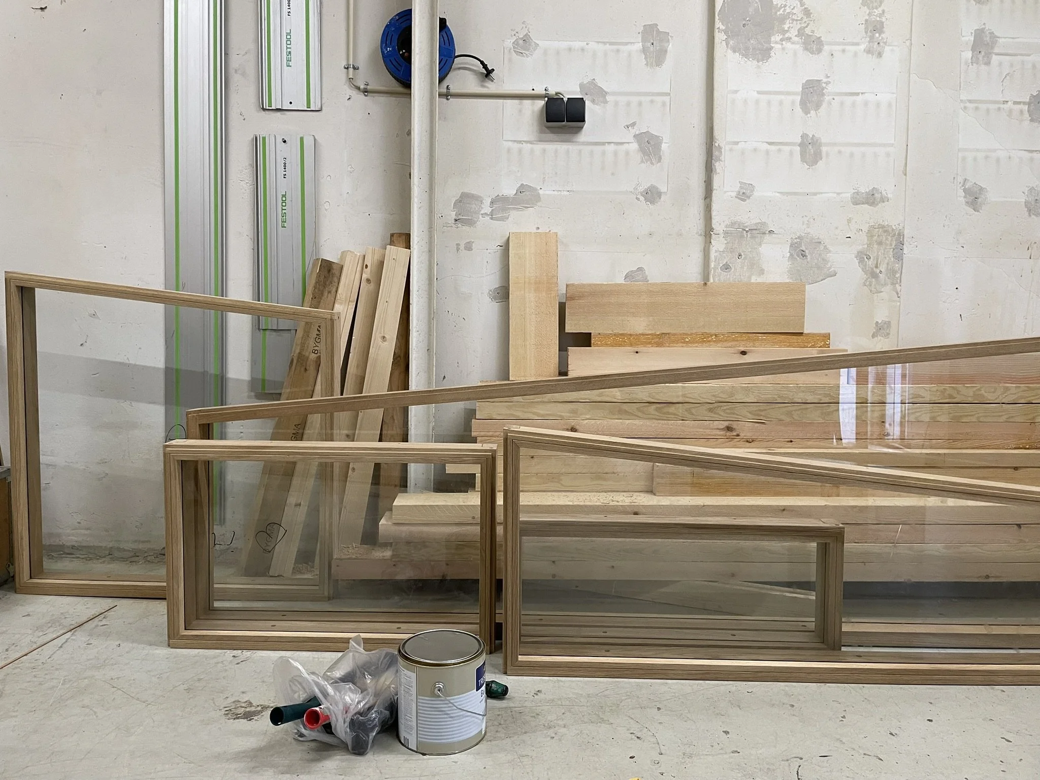 Færdiggørelse af indretning, herunder vinduesrammer, træplanker og værktøj i et rum under renovering.