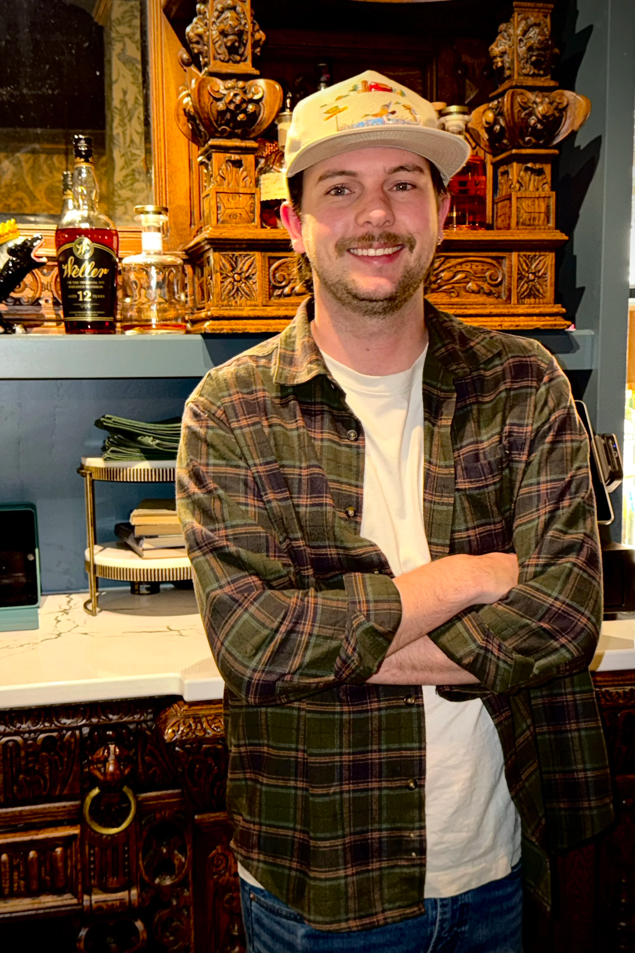 Carter, lead mixologist at 1854 Cocktail Bar & Lounge, smiling in front of the bar in Cookeville TN.