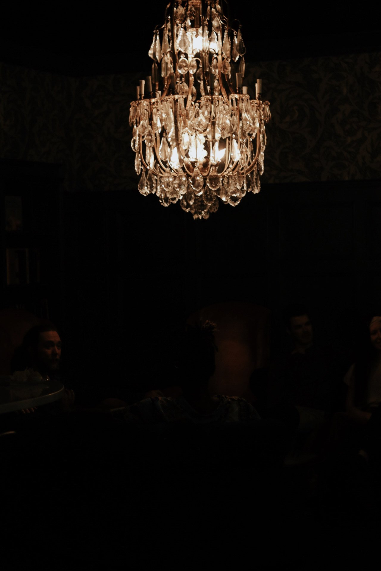 dimly lit bar area showing a glowing chandelier.