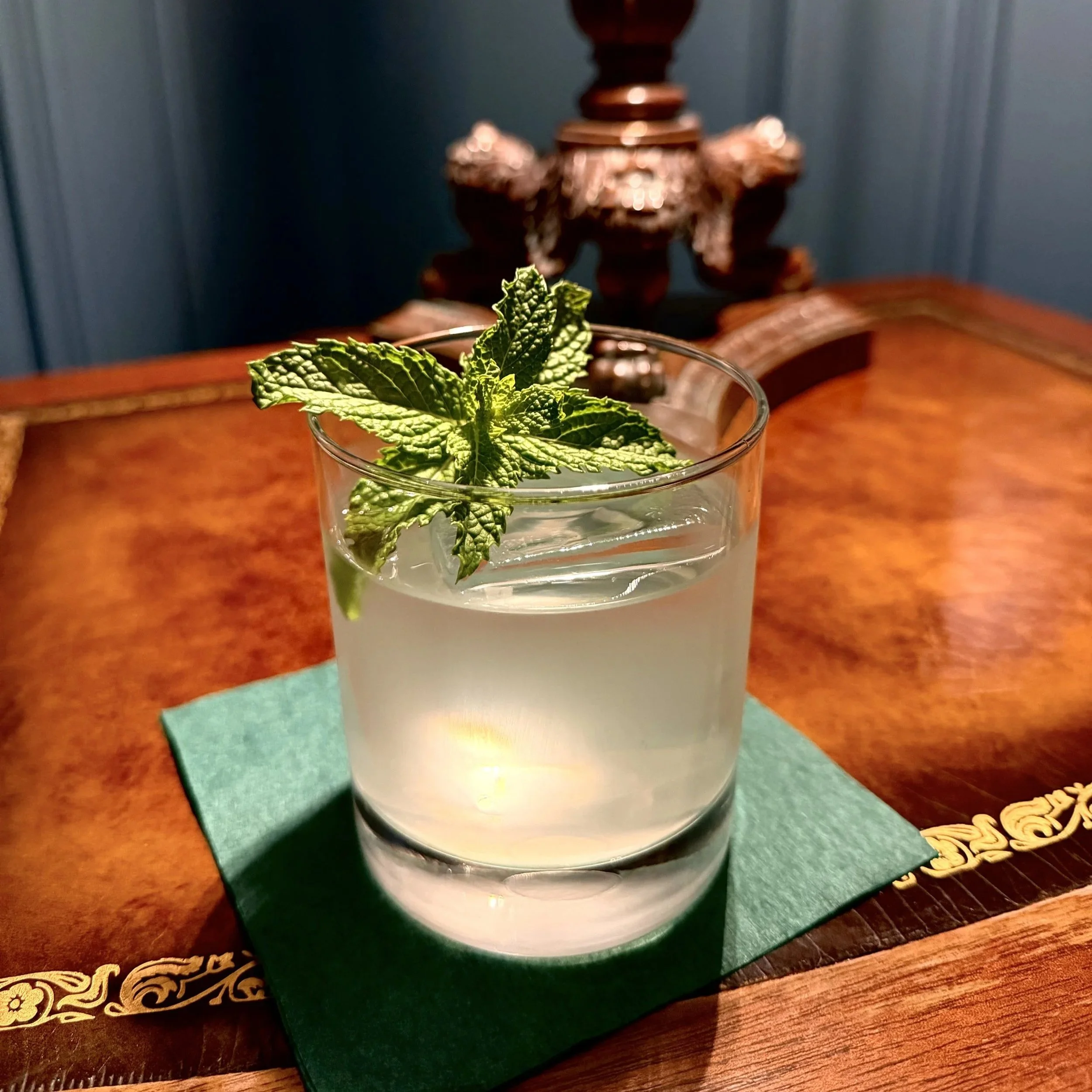 Crystal-clear clarified milk punch cocktail served with fresh mint garnish over a clear ice cube at 1854 Cocktail Bar & Lounge in Cookeville TN.