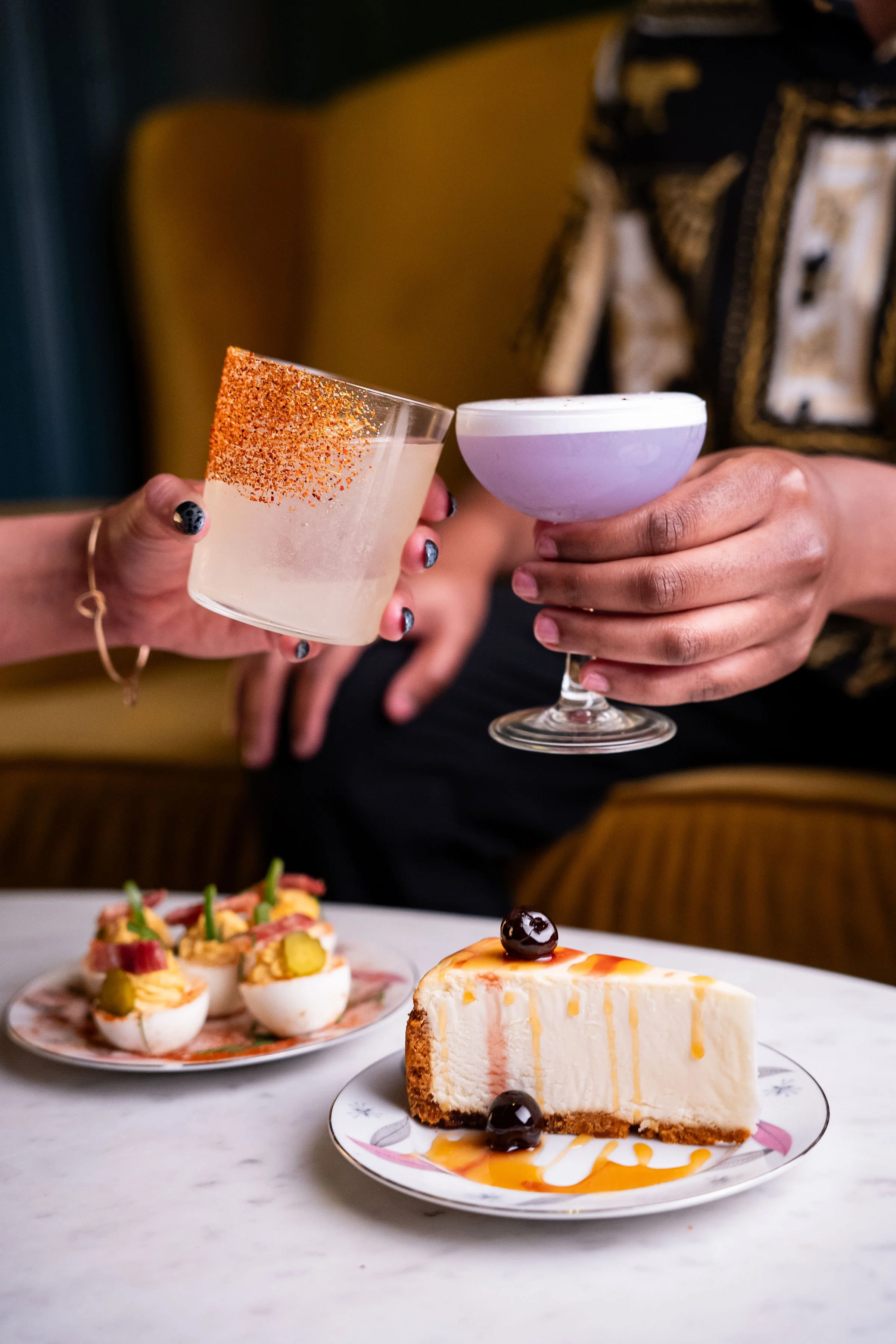 Small plates of deviled eggs and a cheese cake on a marble counter.