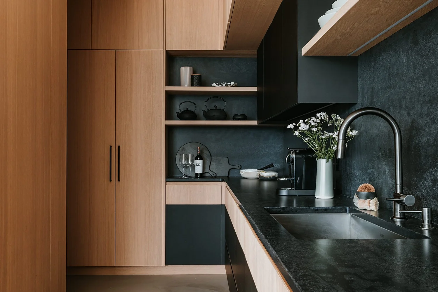 Sunstone Kitchen corner near pantry, oak millwork, wine storage, black cabinetry — new-build interior design in Pemberton, BC by LRD Studio. Photography by Darby Magill.