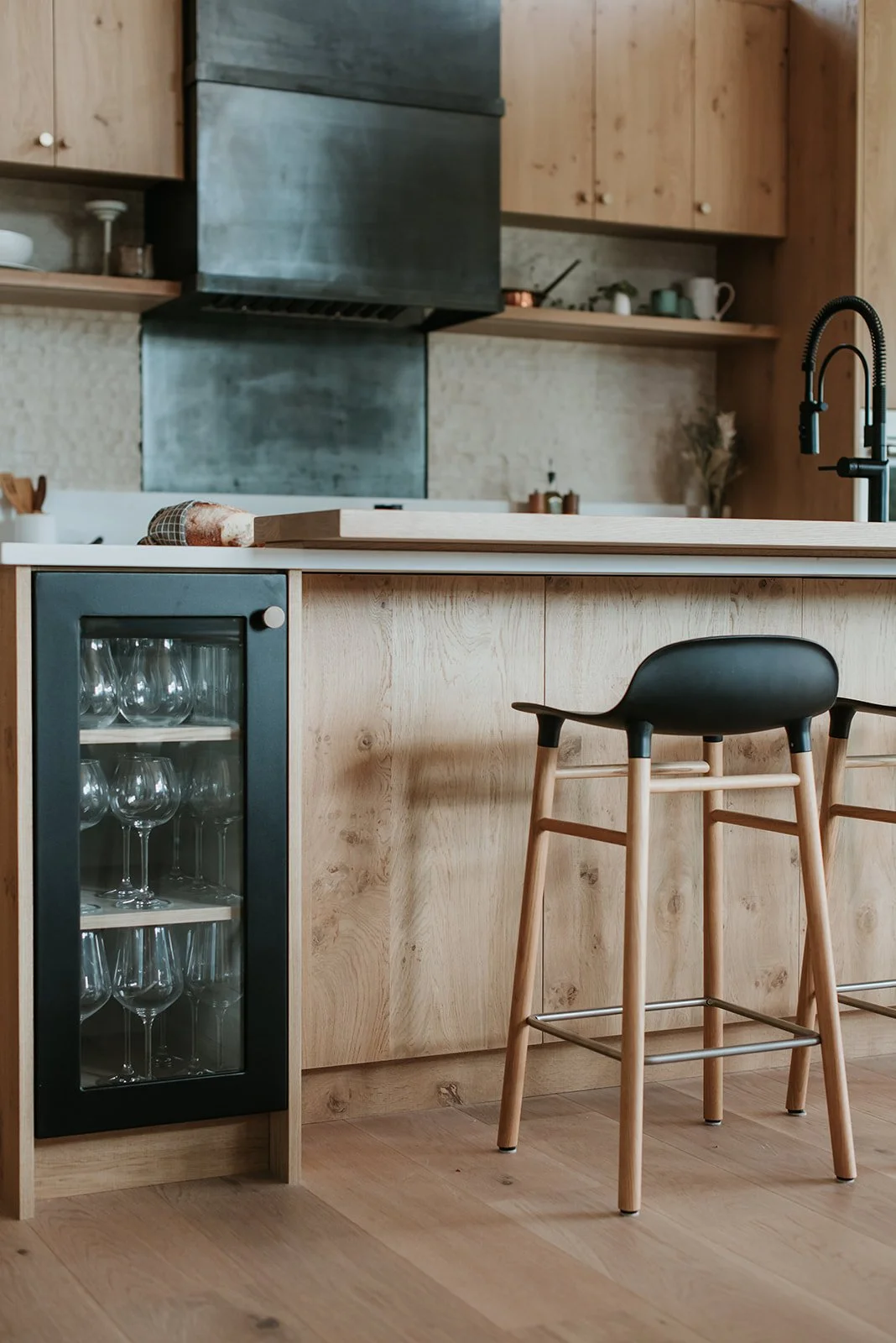 Balsam Island bar detail: rustic oak panels, glass-front glassware cabinet, black stool — new-build interior design in Whistler, BC by LRD Studio. Photography by Darby Magill.