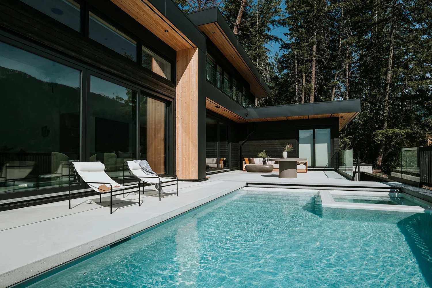 Sunstone Pool and deck with Pemberton mountain views, cedar siding, outdoor furniture — new-build interior design in Pemberton, BC by LRD Studio. Photography by Darby Magill.