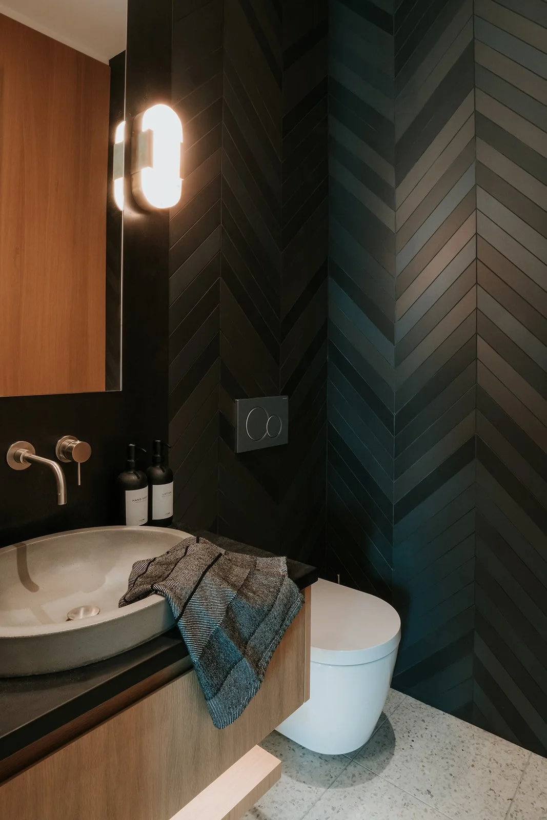 Sunstone Powder room with matte black chevron tile, vessel sink, wall-mount faucet — new-build interior design in Pemberton, BC by LRD Studio. Photography by Darby Magill.