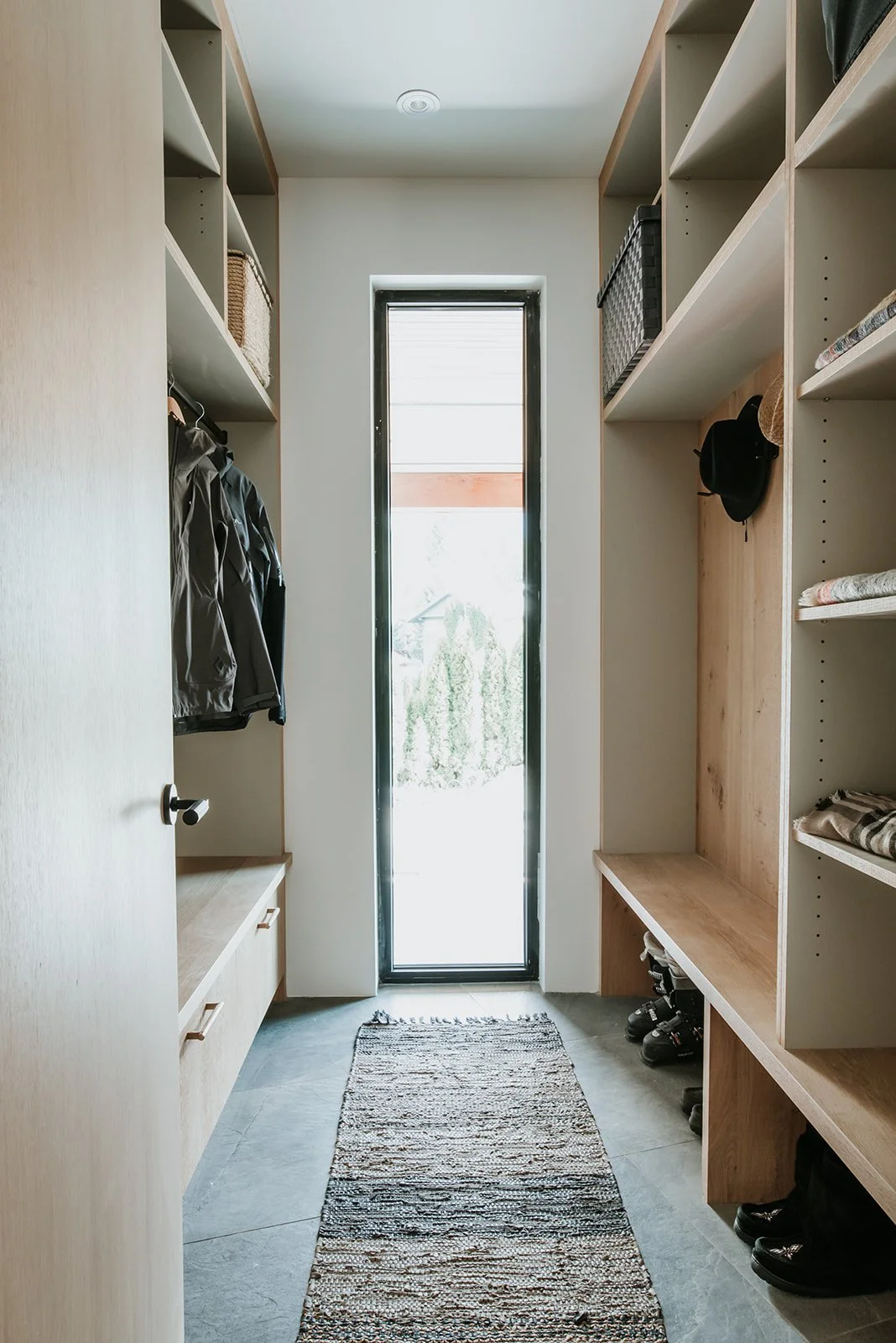 Balsam Ocean black natural stone wall, backlit round mirror, floating oak+black carmana vanity — new-build interior design in Whistler, BC by LRD Studio. Photography by Darby Magill.
