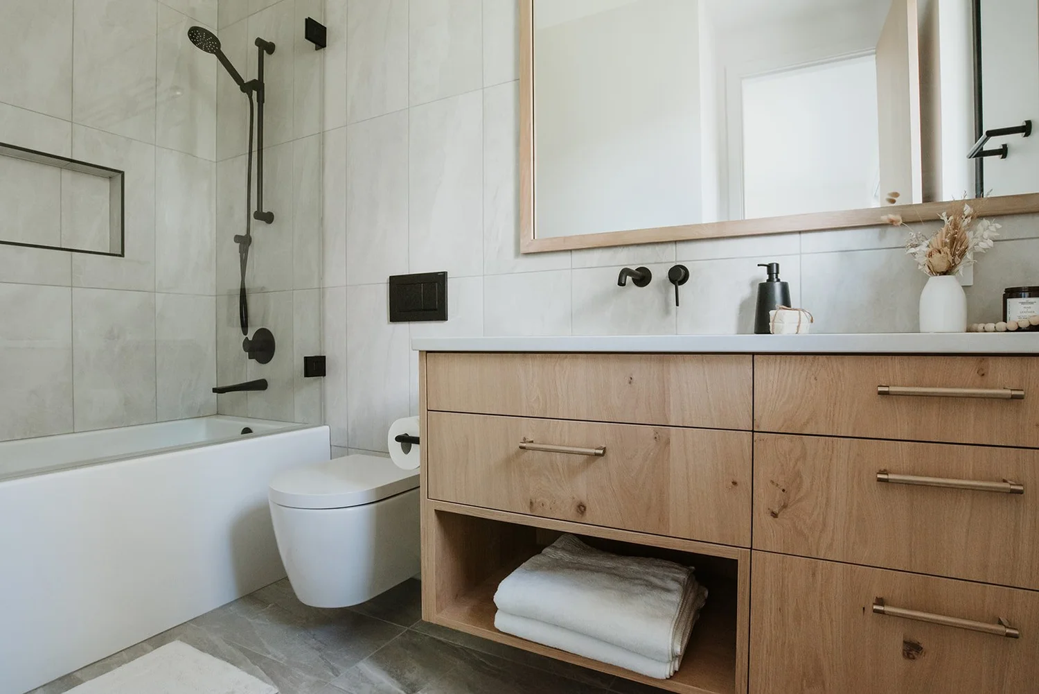 Balsam Oak floating vanity, wall-mount black faucet, oak-framed mirror — new-build interior design in Whistler, BC by LRD Studio. Photography by Darby Magill.