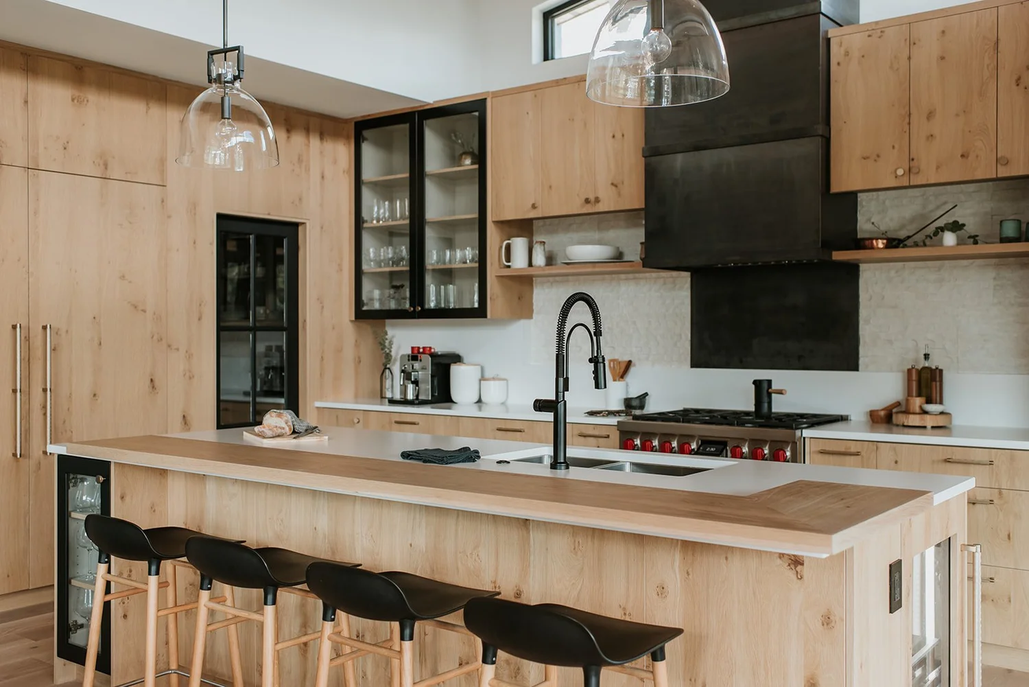 Balsam Alternate angle of full kitchen showing island, stools, glass shaker cabinets, steel hood — new-build interior design in Whistler, BC by LRD Studio. Photography by Darby Magill.