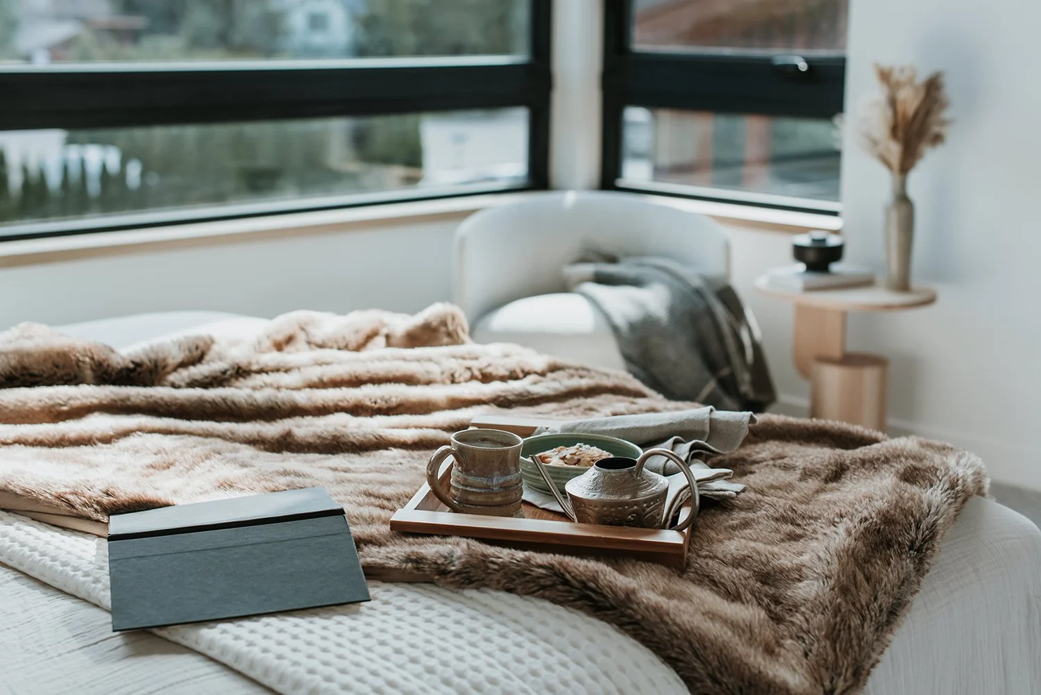 Balsam Breakfast tray close-up on fur throw, mountain view through window — new-build interior design in Whistler, BC by LRD Studio. Photography by Darby Magill.