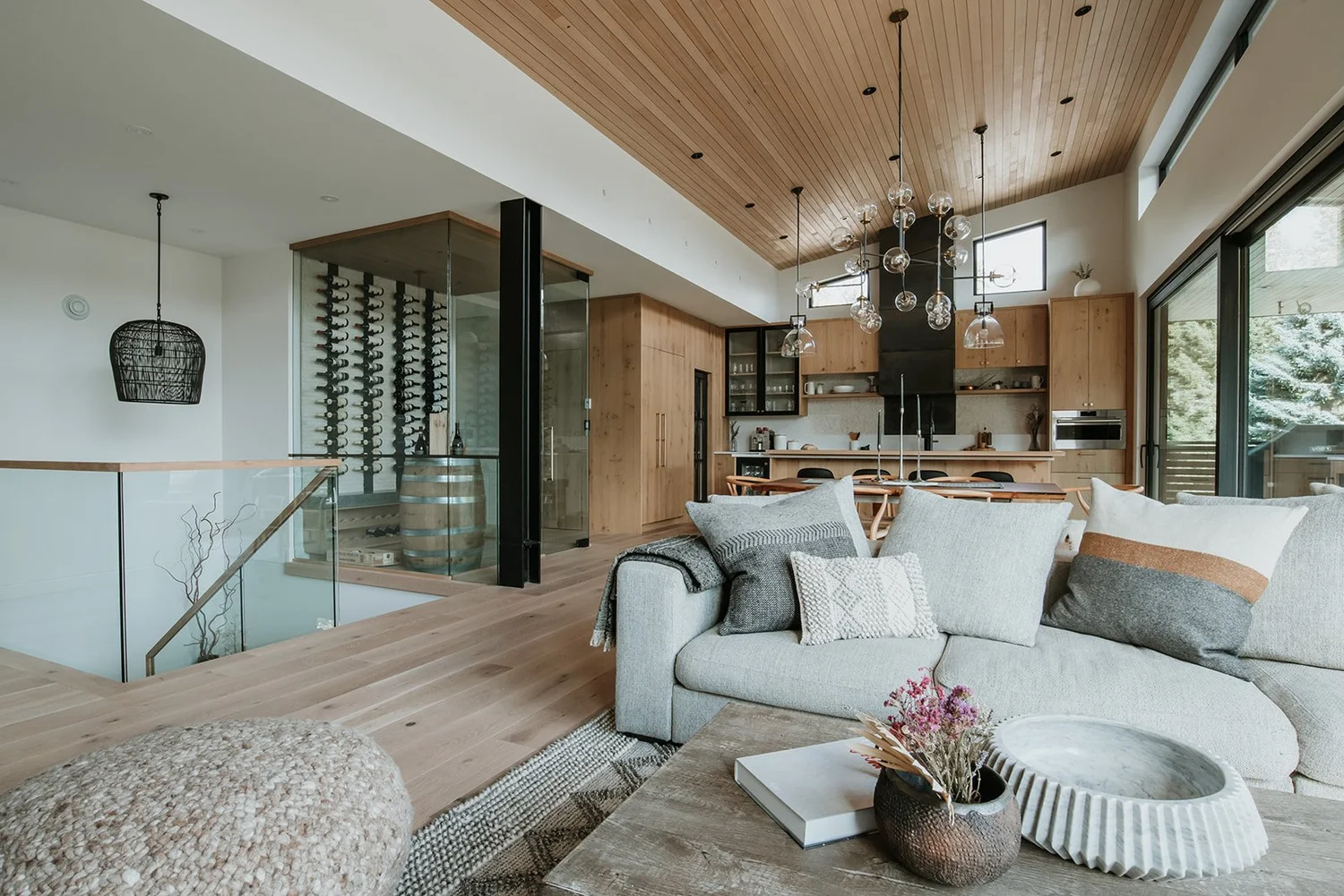 Balsam Wide view showing living room, glass wine room, kitchen beyond, basket-woven pendant — new-build interior design in Whistler, BC by LRD Studio. Photography by Darby Magill.