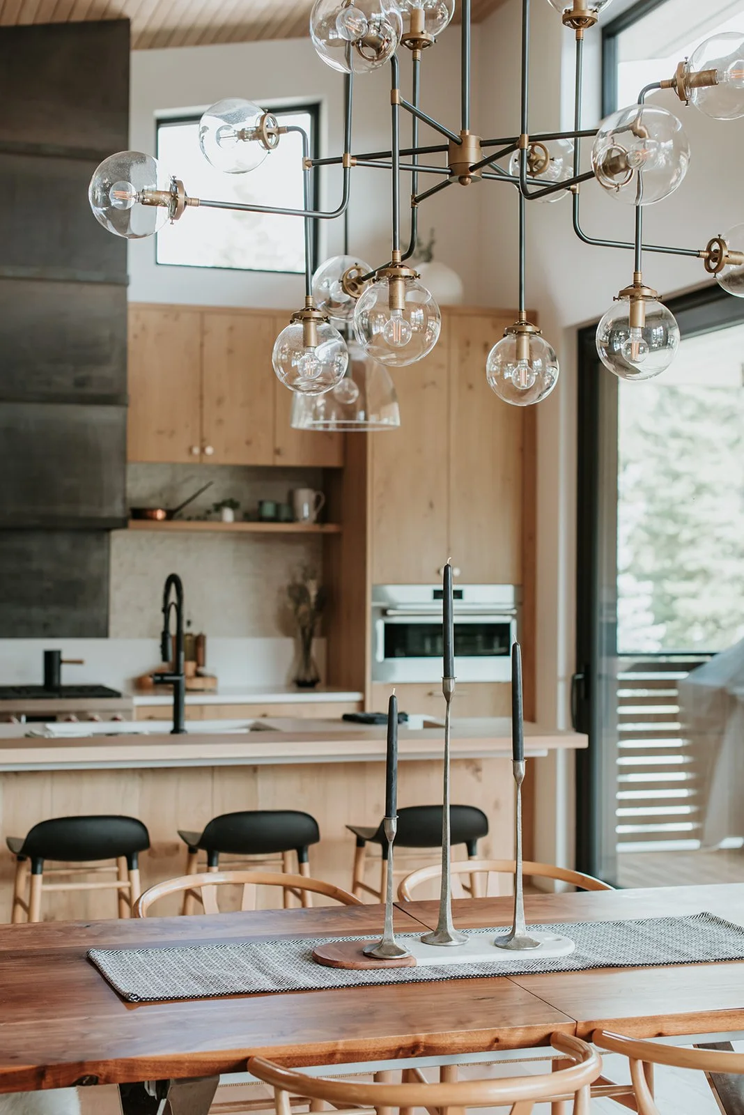Balsam Art deco brass+glass globe chandelier detail over dining table with candelabras — new-build interior design in Whistler, BC by LRD Studio. Photography by Darby Magill.